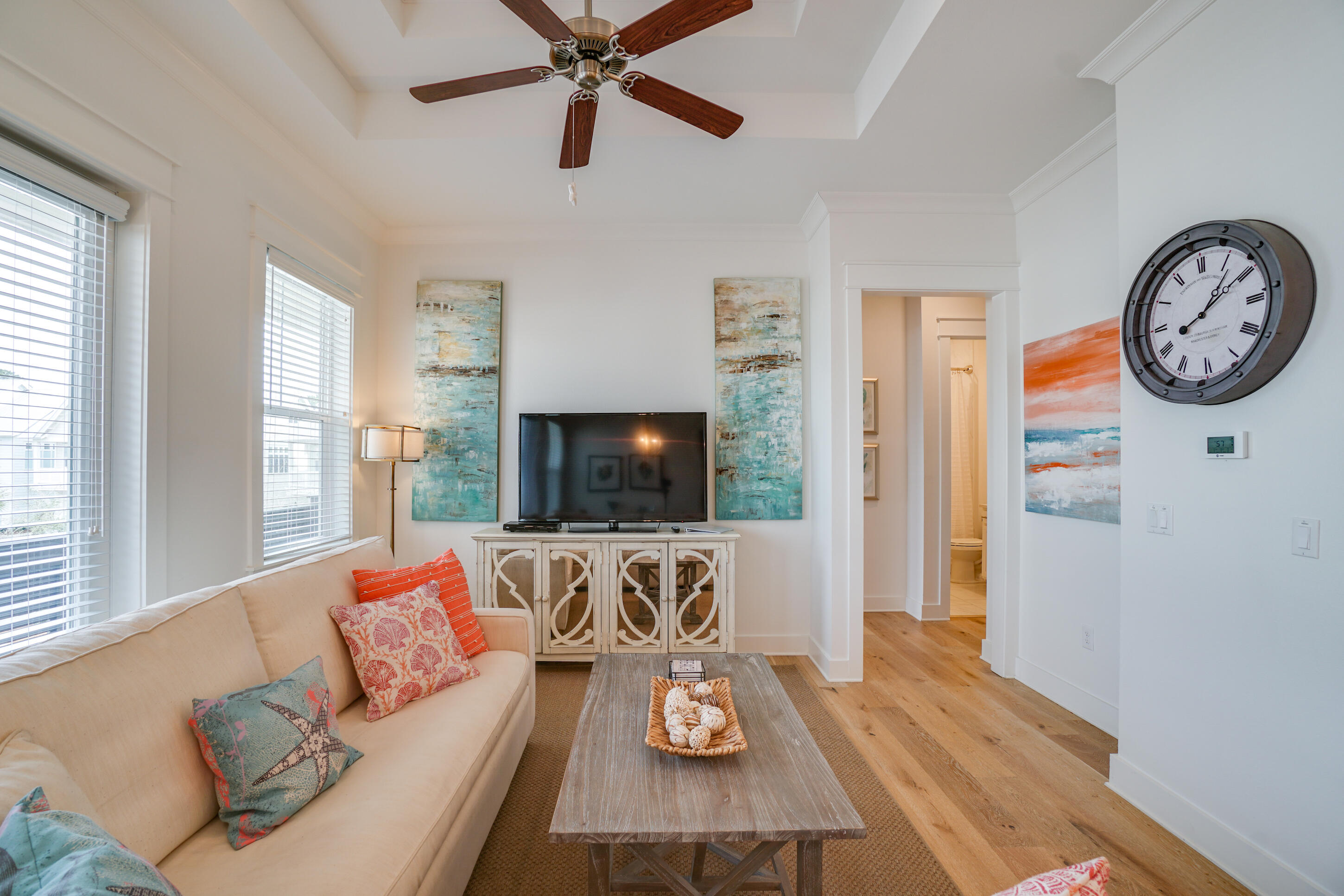 Bright living room with a cream sofa, wood coffee table, and TV between abstract paintings.