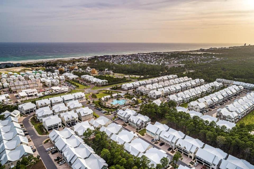 Aerial view of coastal homes and a community pool beside the ocean at golden hour.