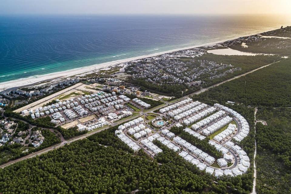 Aerial view of coastal homes beside a white-sand beach and turquoise Gulf water.