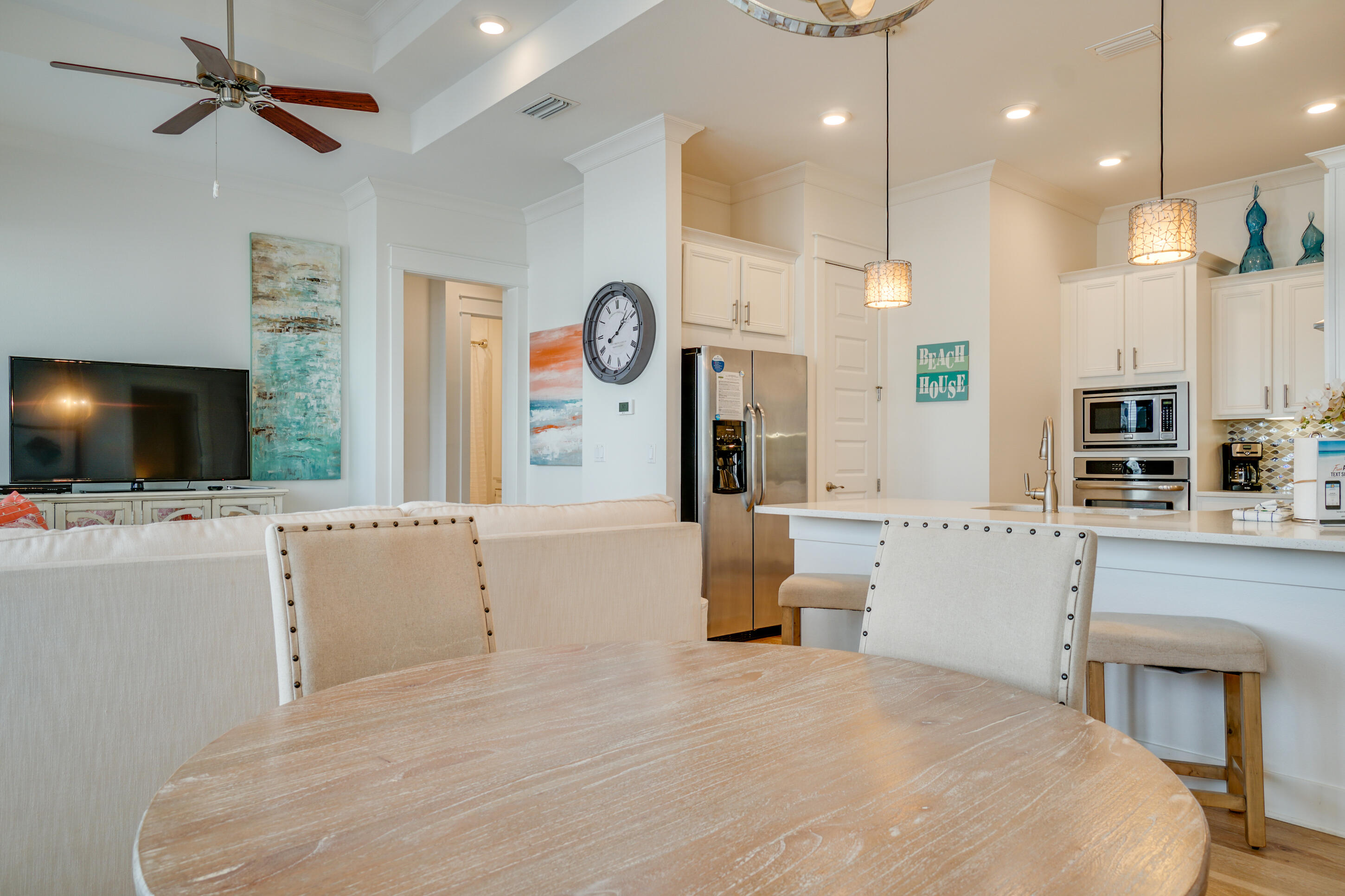 Open-plan kitchen and dining area with a large island, white cabinetry, and coastal decor.