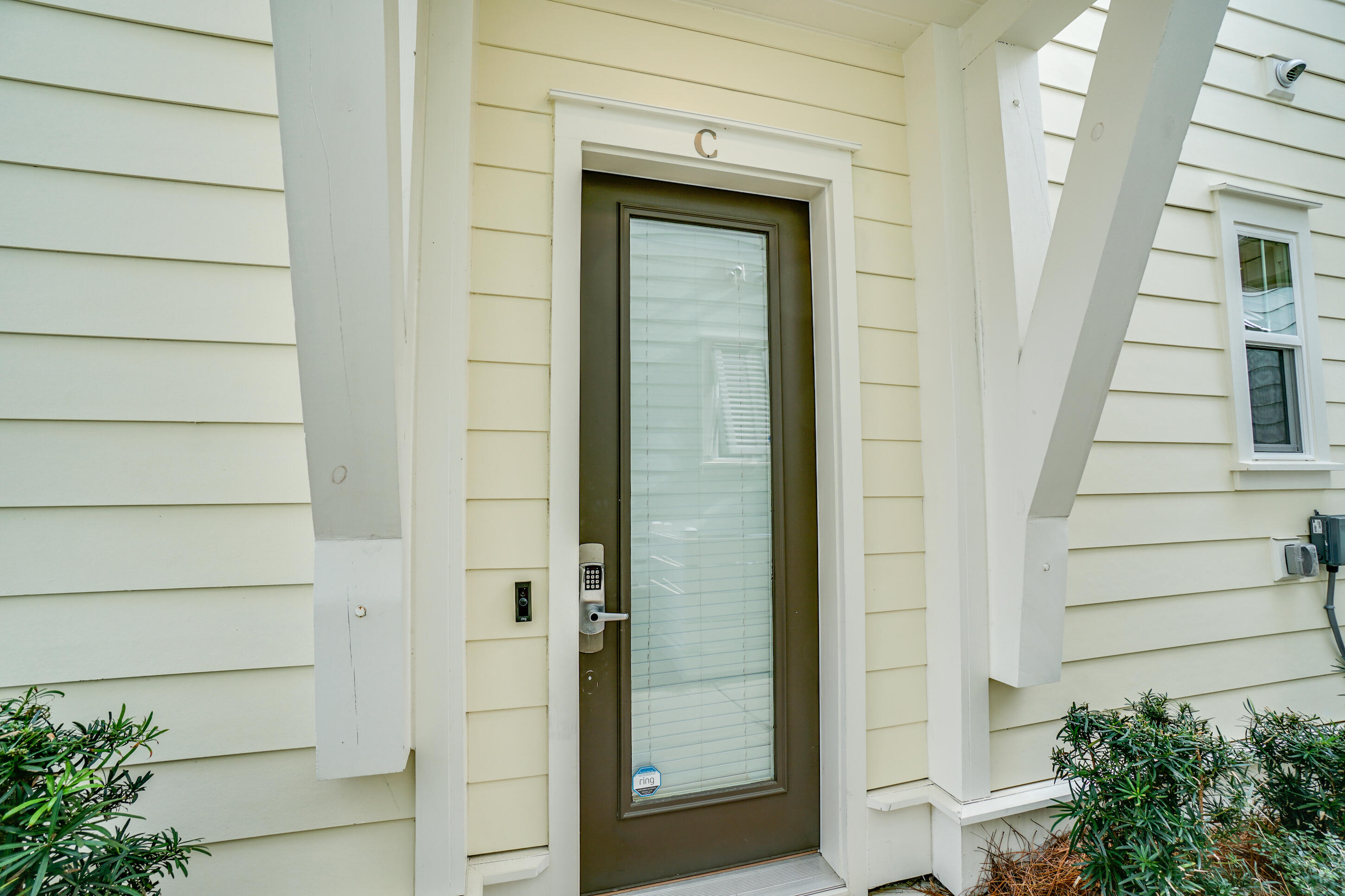 Home entrance with a glass-panel door marked C, electronic keypad lock, and white porch supports.