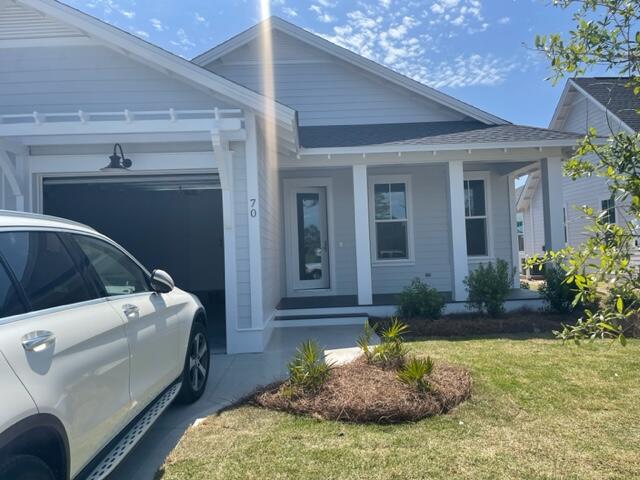 Gray single-story home with a dark garage, covered entry, and white SUV in the driveway.