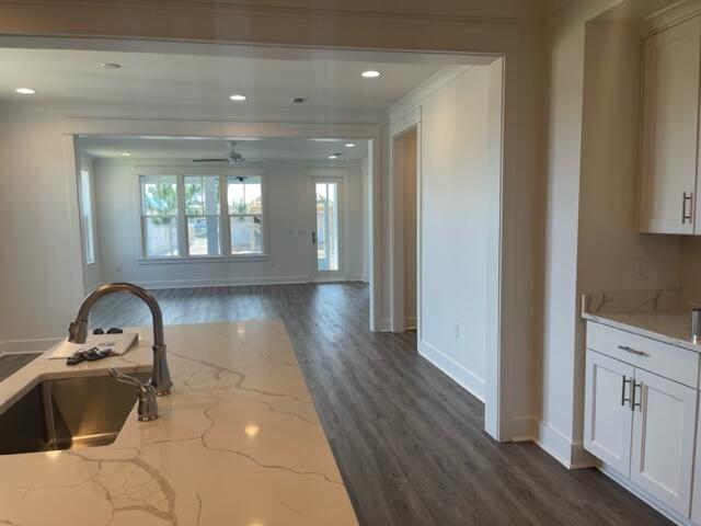 Kitchen island with a sink opens onto a living area with large windows and dark flooring.