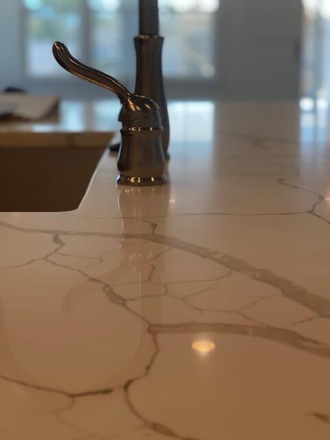 Kitchen countertop with gray veining, dark sink, and bronze faucet.