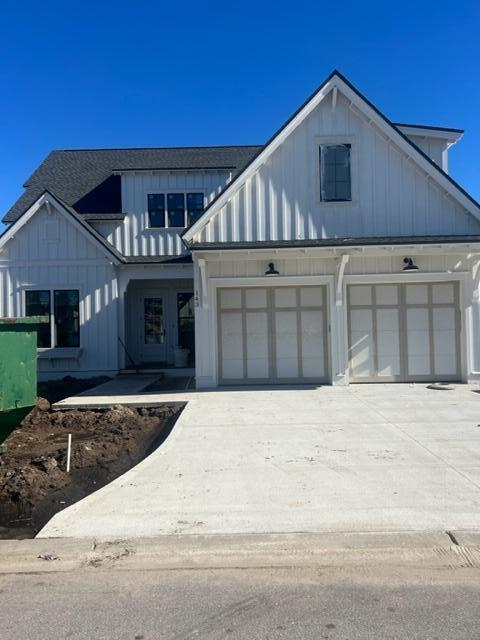 White two-story home with a prominent front gable, double garage, and broad concrete driveway.