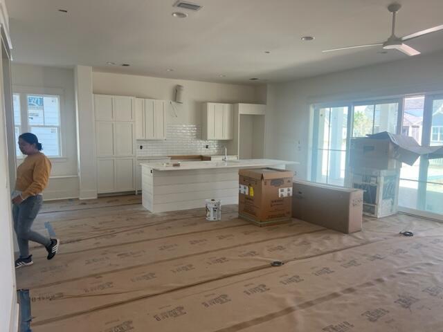 Kitchen under construction with white cabinetry, a large island, and protective paper covering the floor.