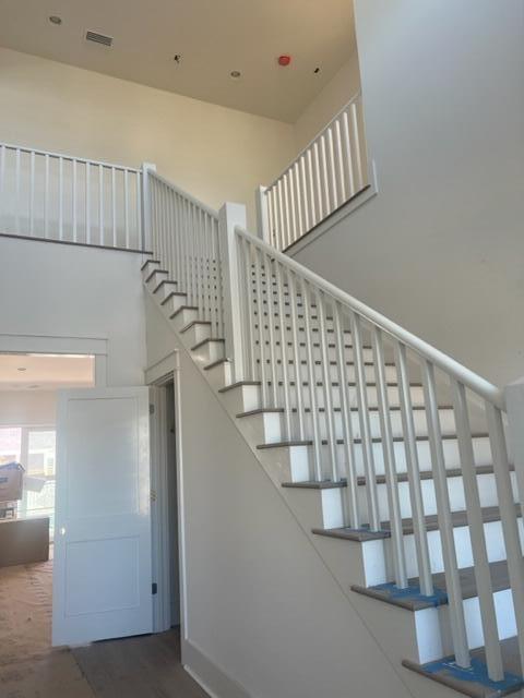 Two-story staircase with white railings, dark wood treads, and a high ceiling.