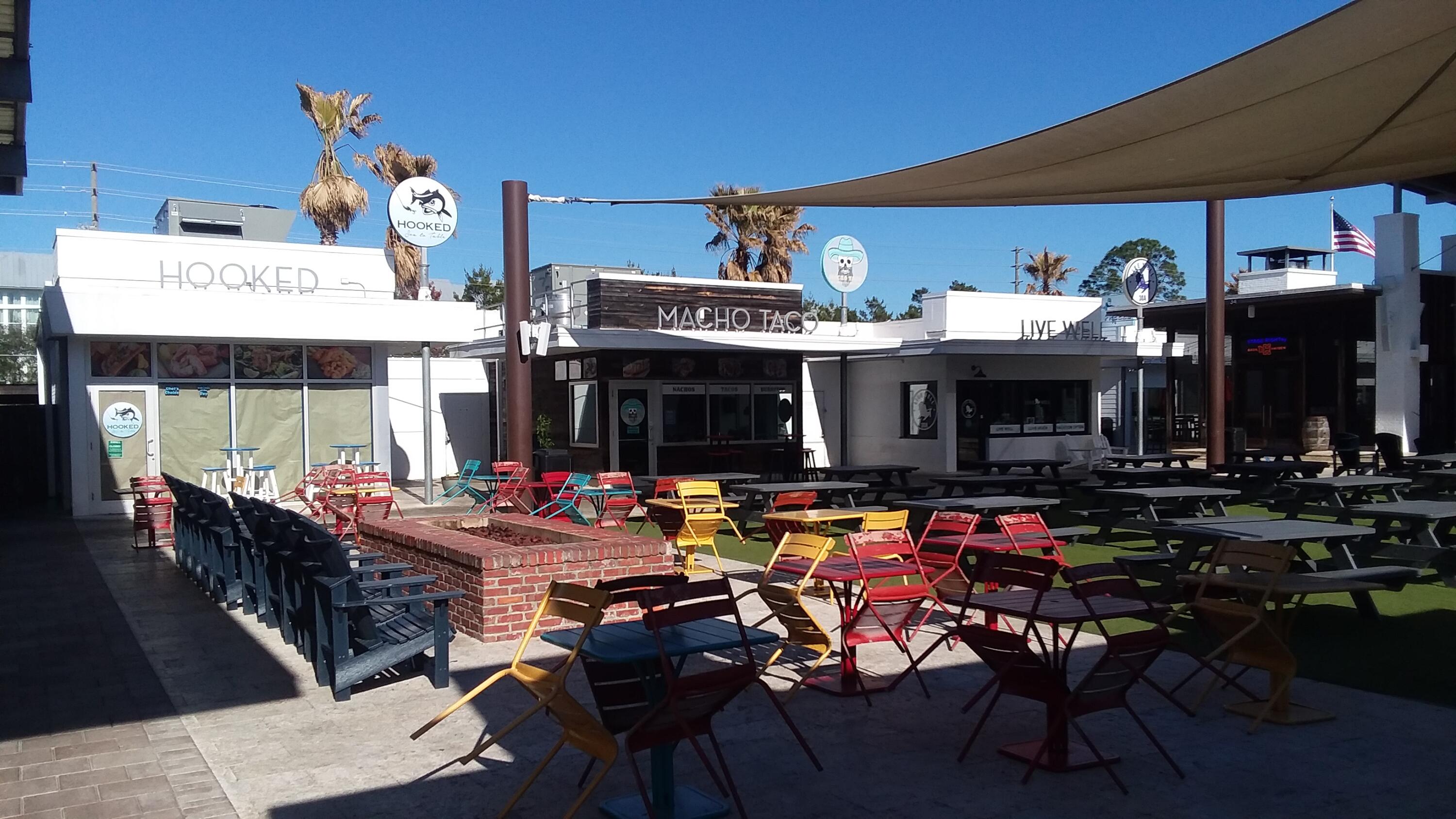 Restaurant courtyard with colorful café seating beneath a shade sail.