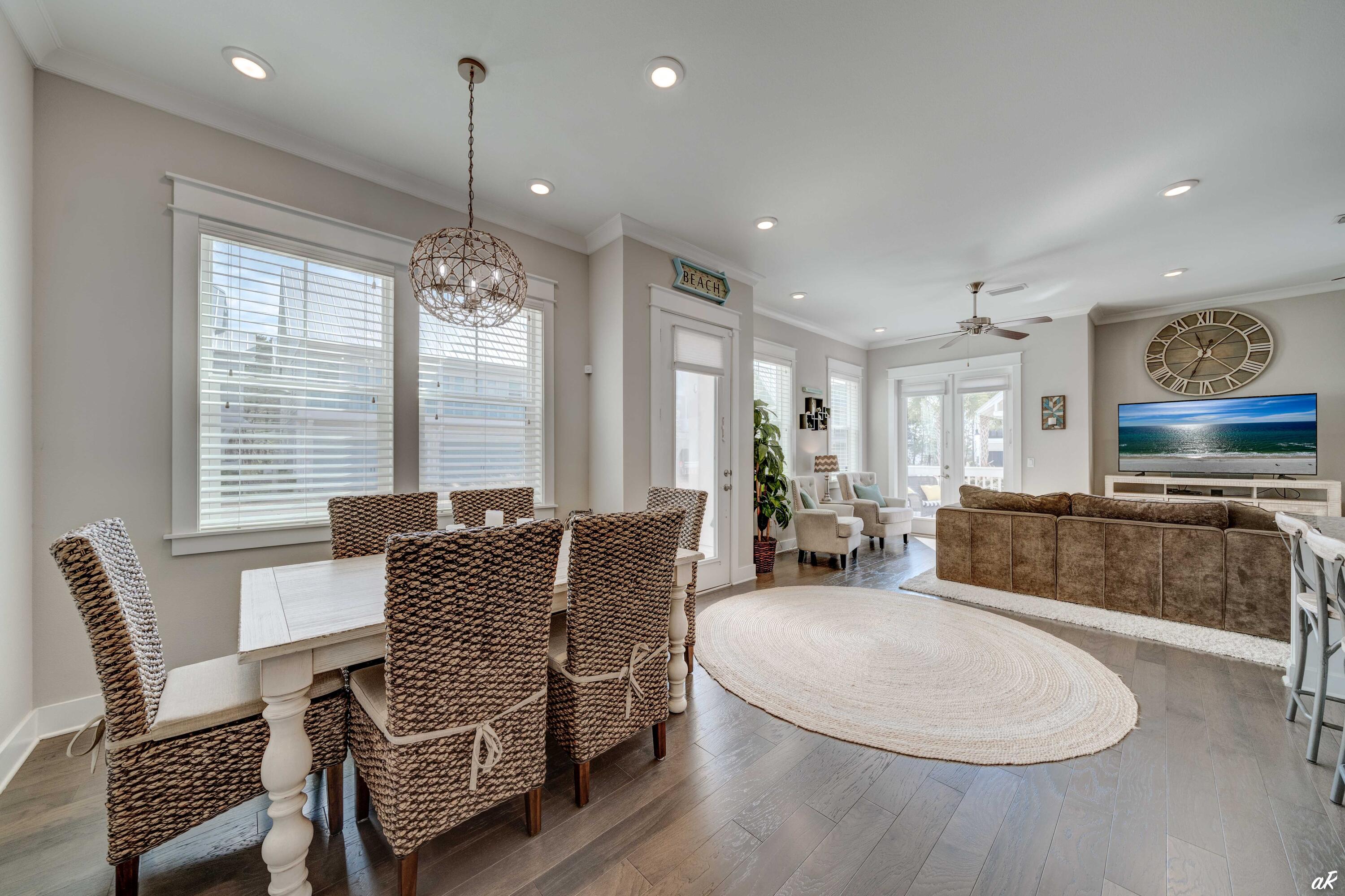 Open-plan dining and living room with woven chairs, a brown sectional, and a large round rug.