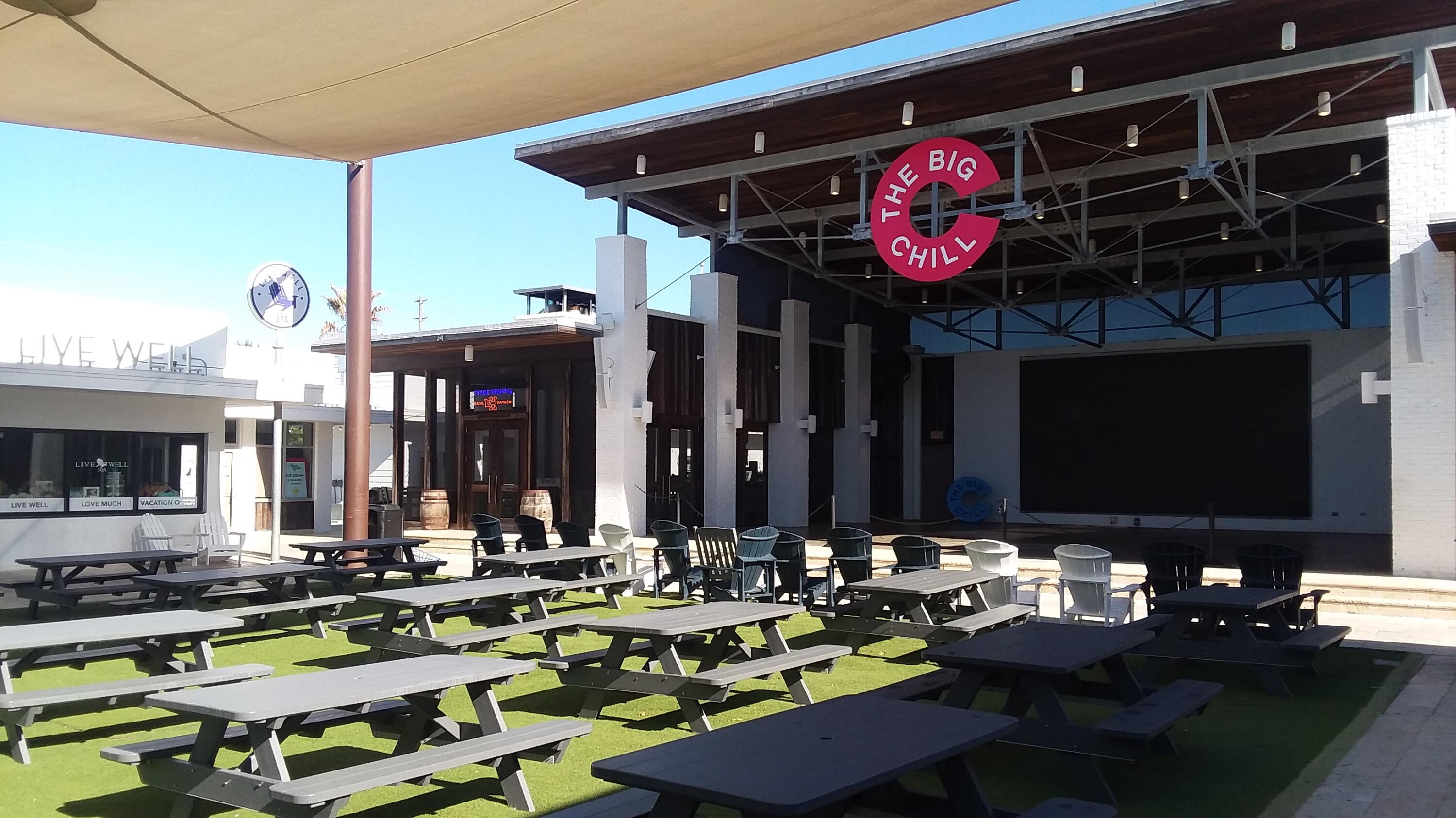 The Big Chill outdoor venue with picnic tables, a covered stage, and a large screen.