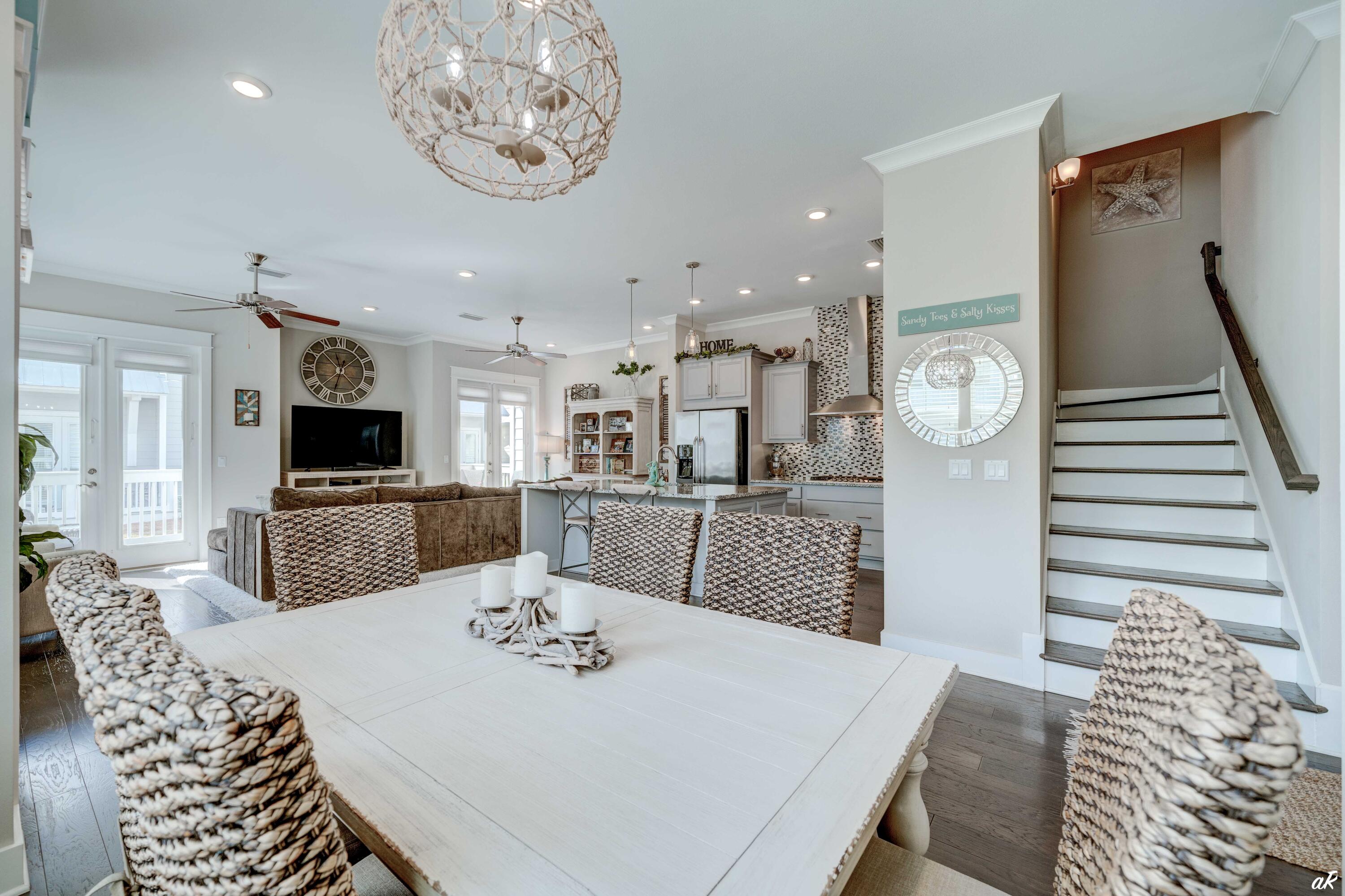 Open-plan dining room, living area, and kitchen with woven chairs and a staircase.