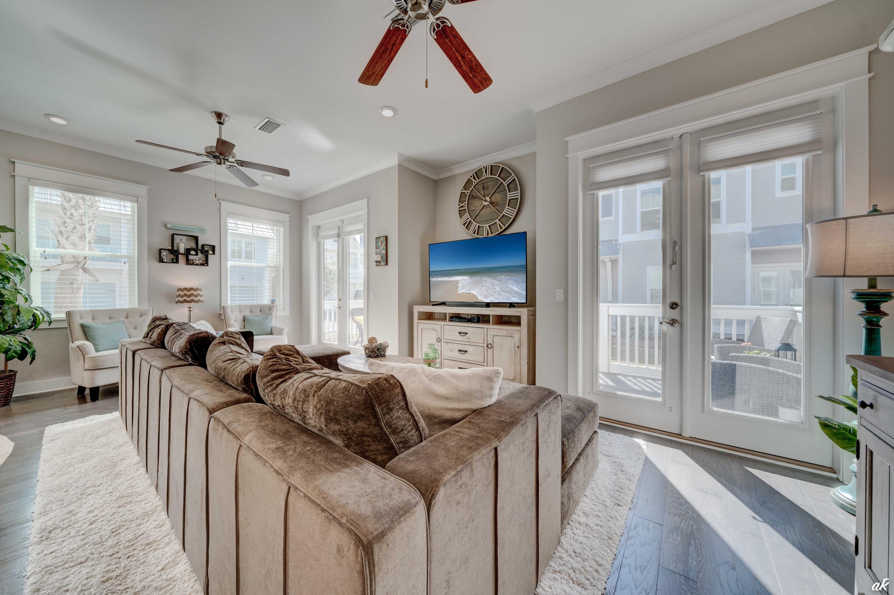 Furnished living room with a large sectional sofa, beach-scene television, and glass doors to a porch.