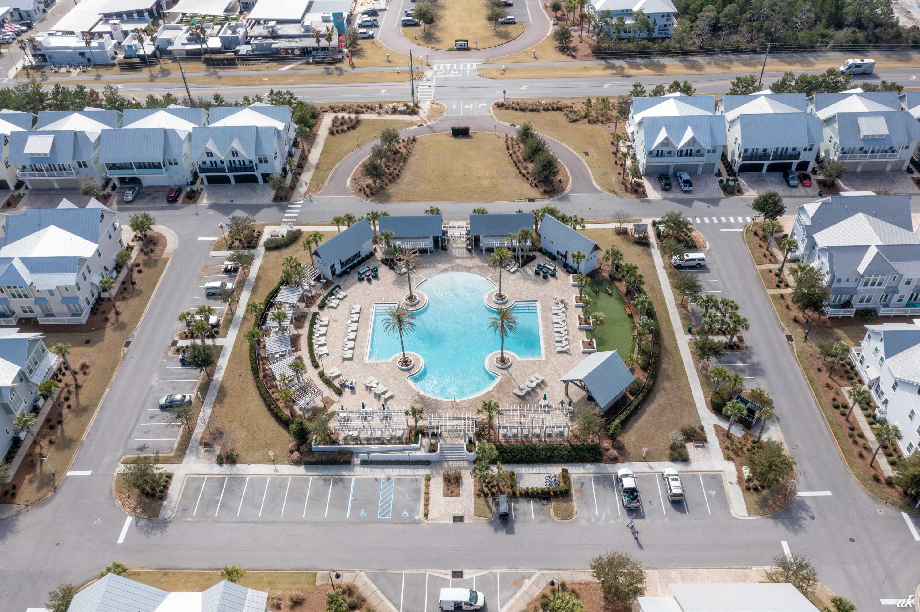 Aerial view of a community pool surrounded by homes, palm trees, and lounge chairs.
