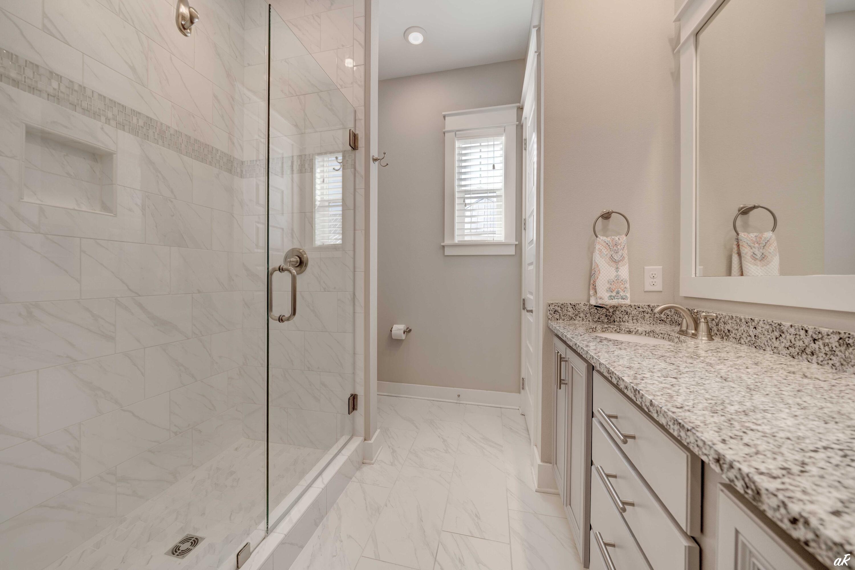 Bathroom with a marble-tile glass shower and long granite vanity.