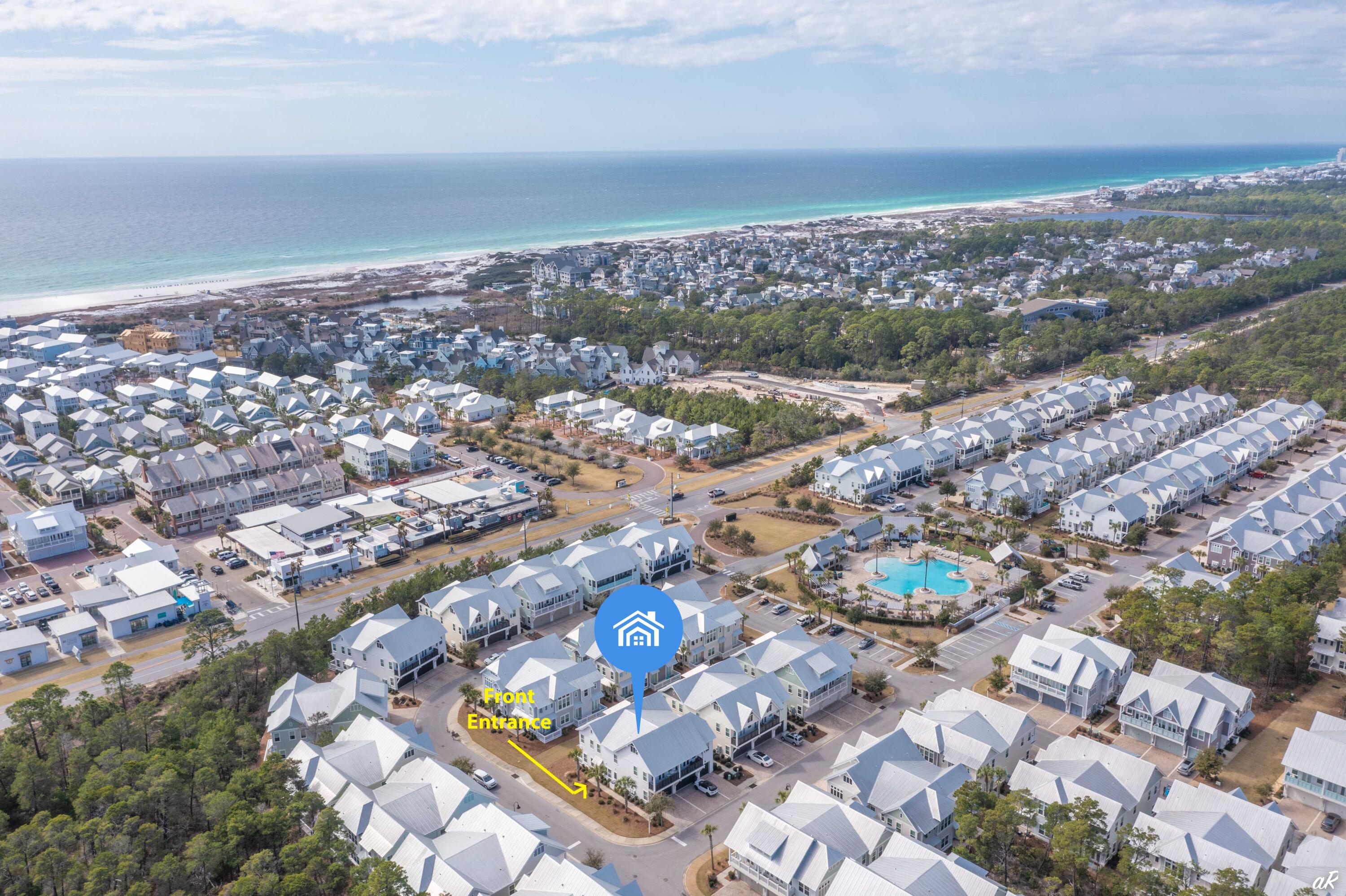 Aerial view of coastal homes with the marked front entrance, community pool, beach, and ocean.