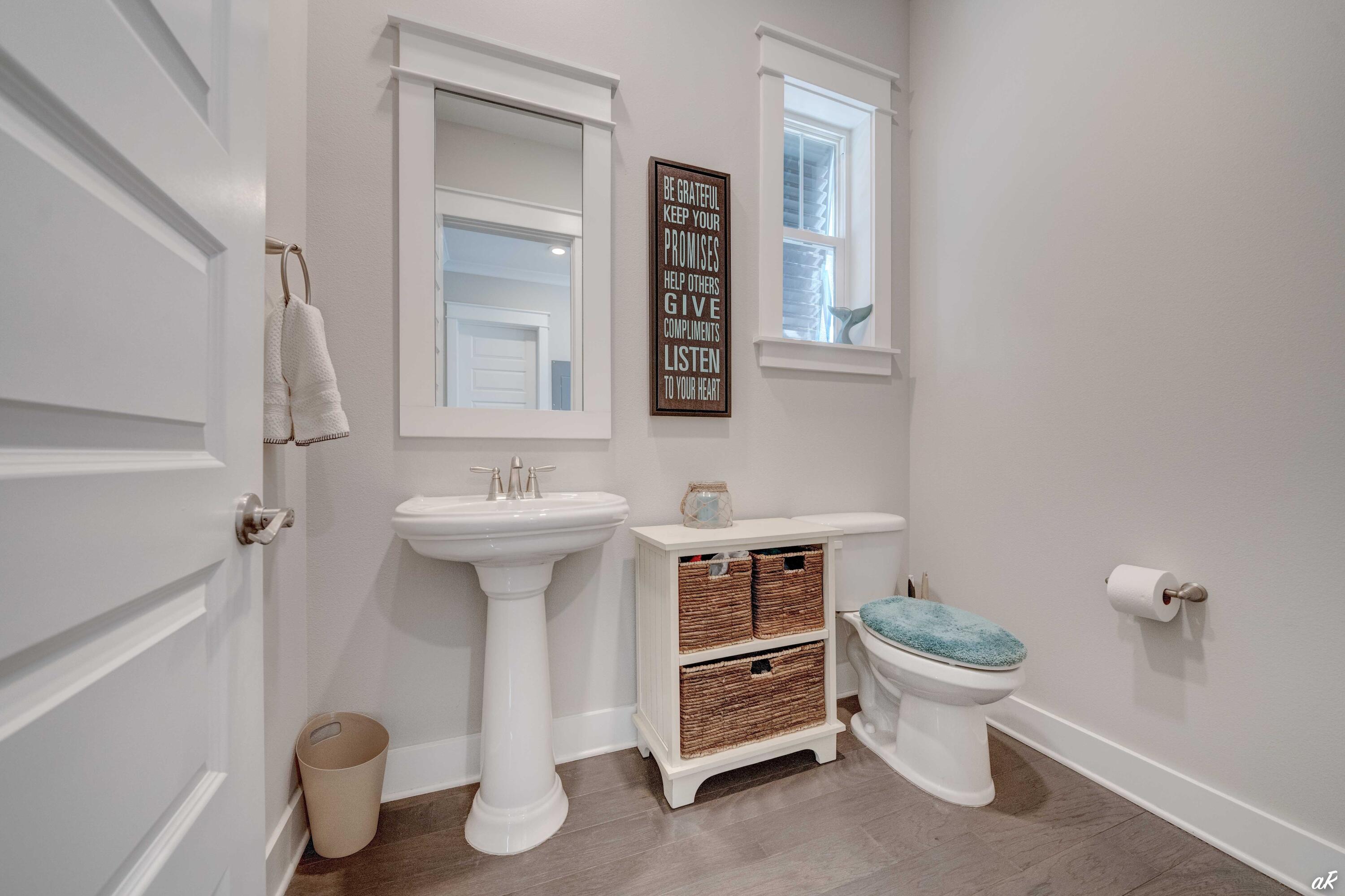 Bathroom with pedestal sink, woven-basket storage, and a toilet with a turquoise seat cover.