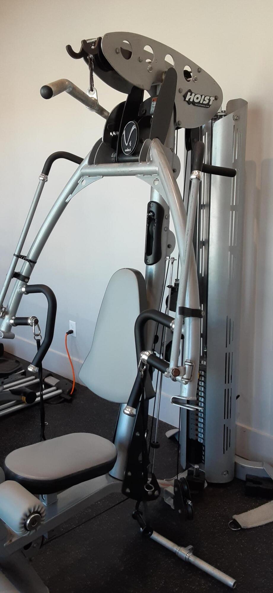 Home gym with a HOIST cable machine, weight stack, and padded seat.