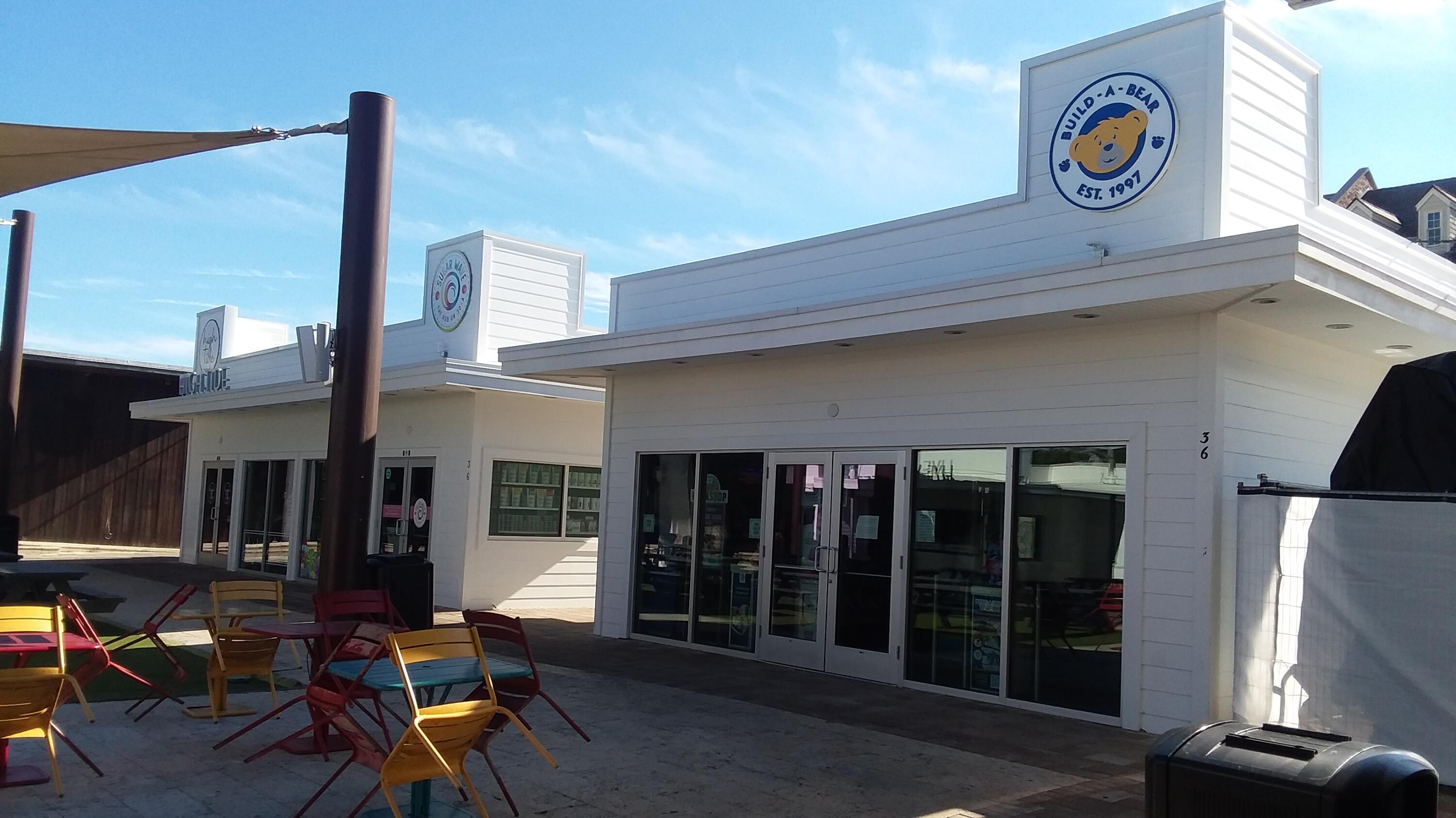 White storefront with a Build-A-Bear sign and colorful outdoor patio seating.
