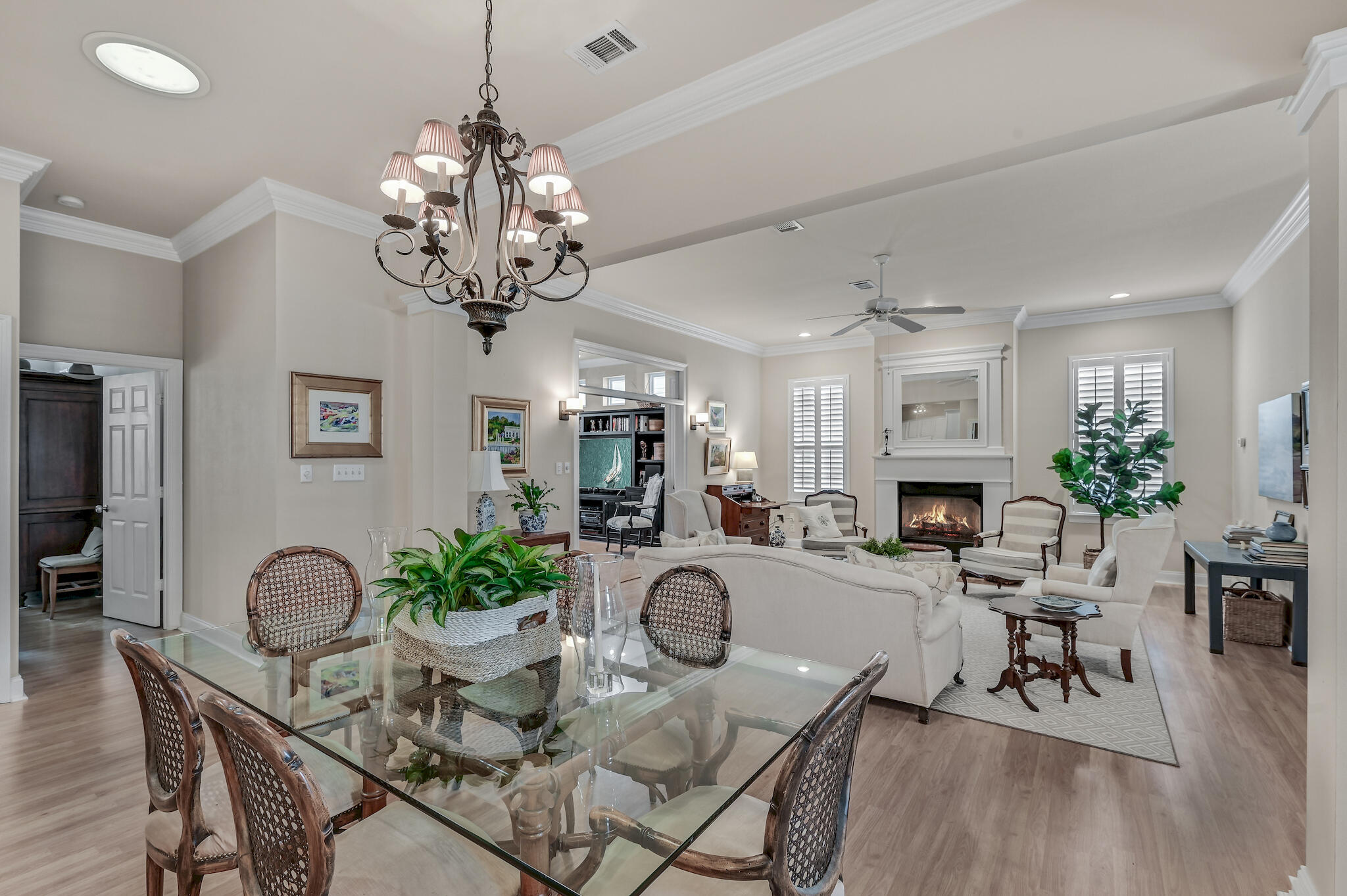 Open-plan living and dining room with a glass table, chandelier, and fireplace.