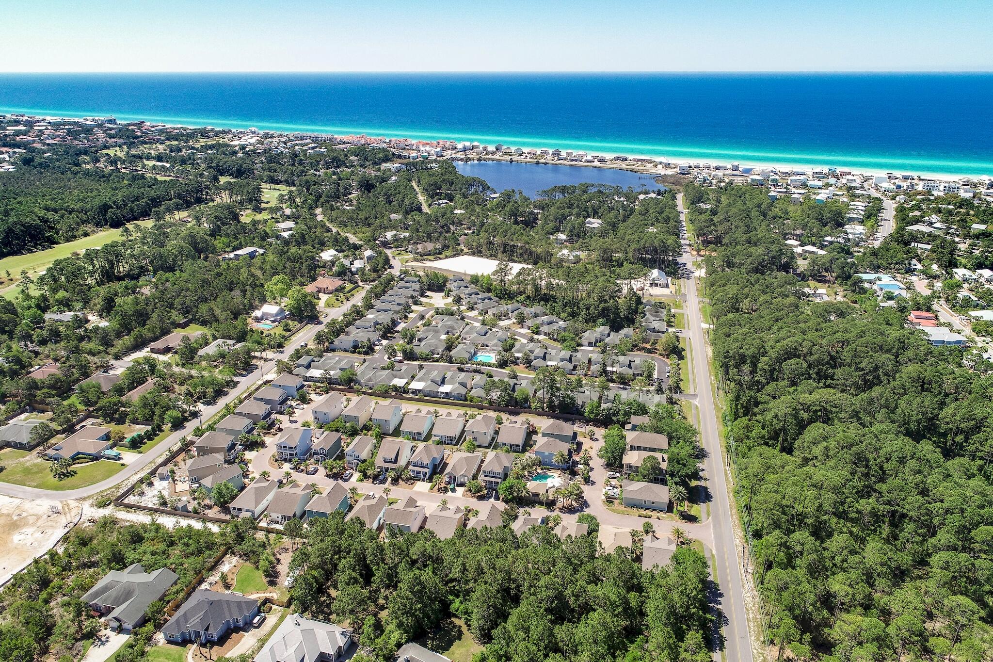 Aerial view of a coastal neighborhood, lagoon, pine woods, and Gulf beach.