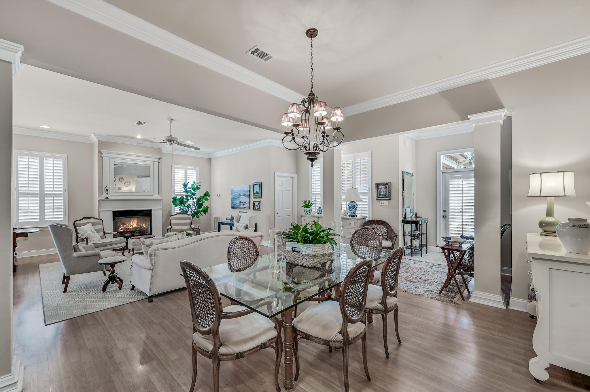 Open-plan living and dining room with a fireplace, glass dining table, and chandelier.