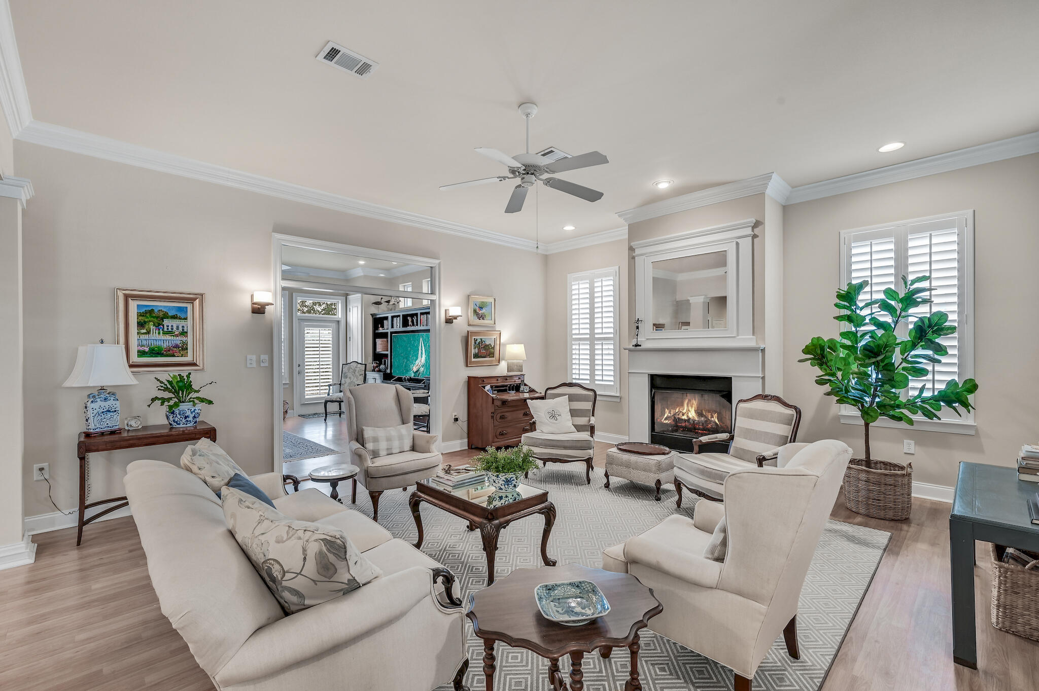 Furnished living room with a white fireplace, cream seating, and a large potted plant.