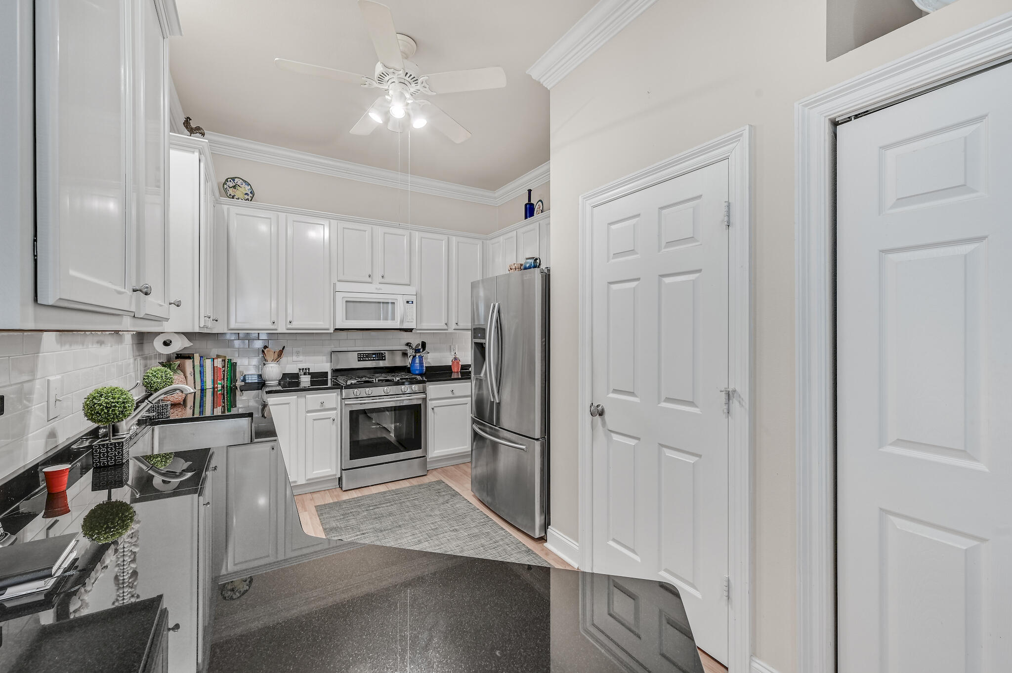 Kitchen with white cabinetry, black countertops, and stainless steel appliances.