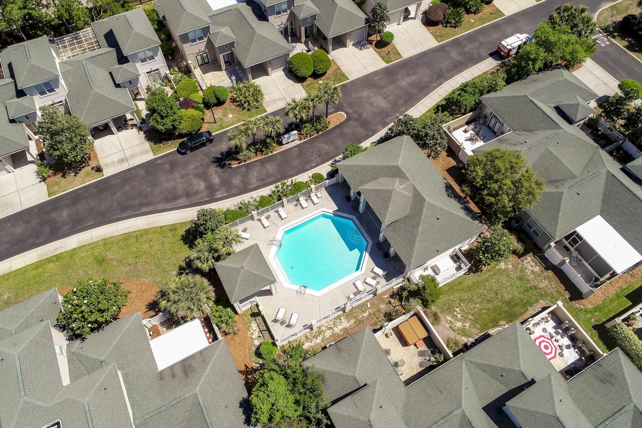 Aerial view of a community pool surrounded by homes and a curved street.