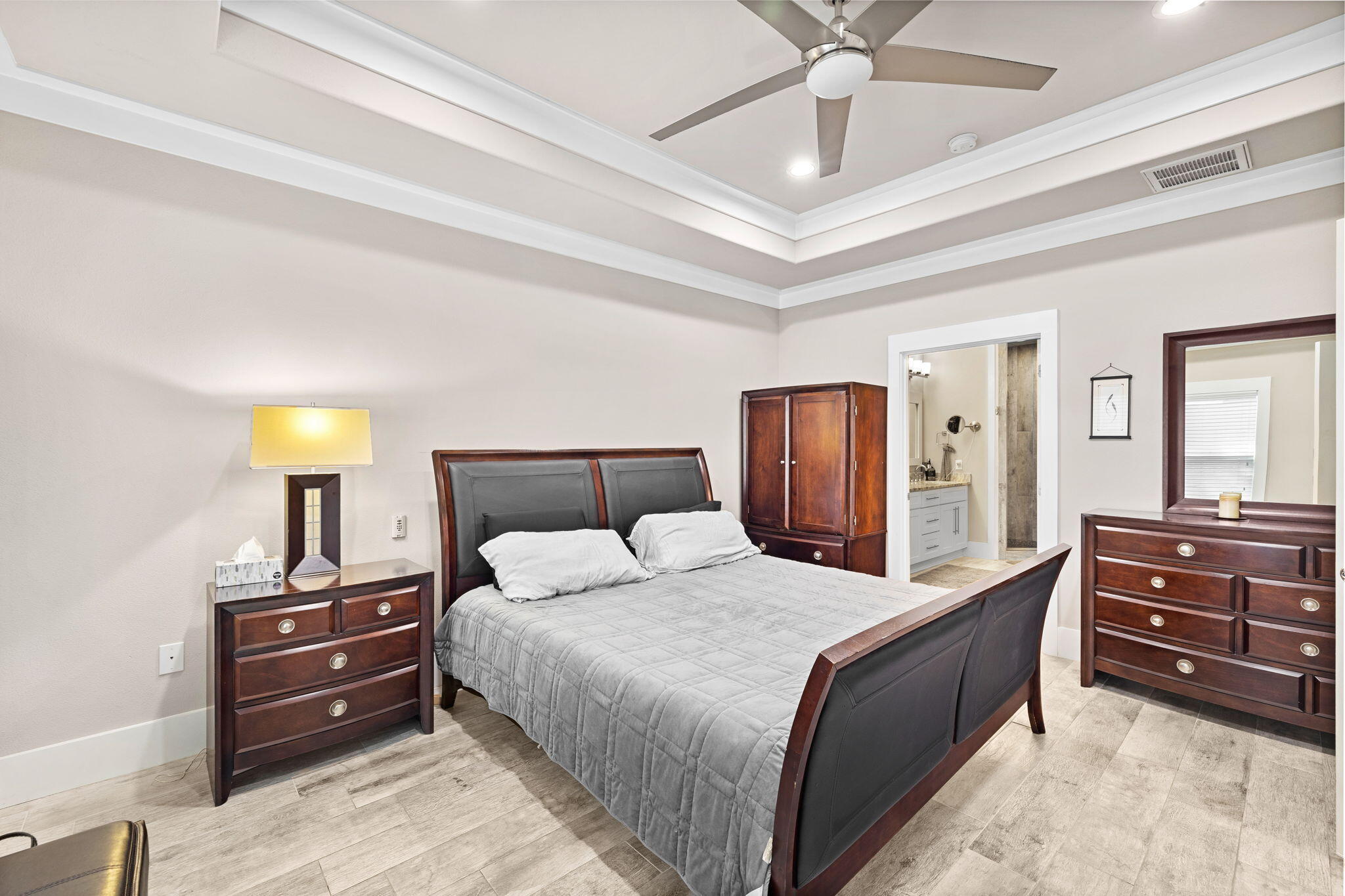 Bedroom with a dark wood bed and matching dressers, plus an open doorway to the ensuite bathroom.