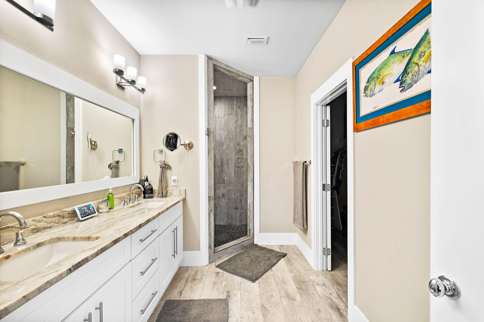 Bathroom with a long double vanity and gray-tiled walk-in shower.