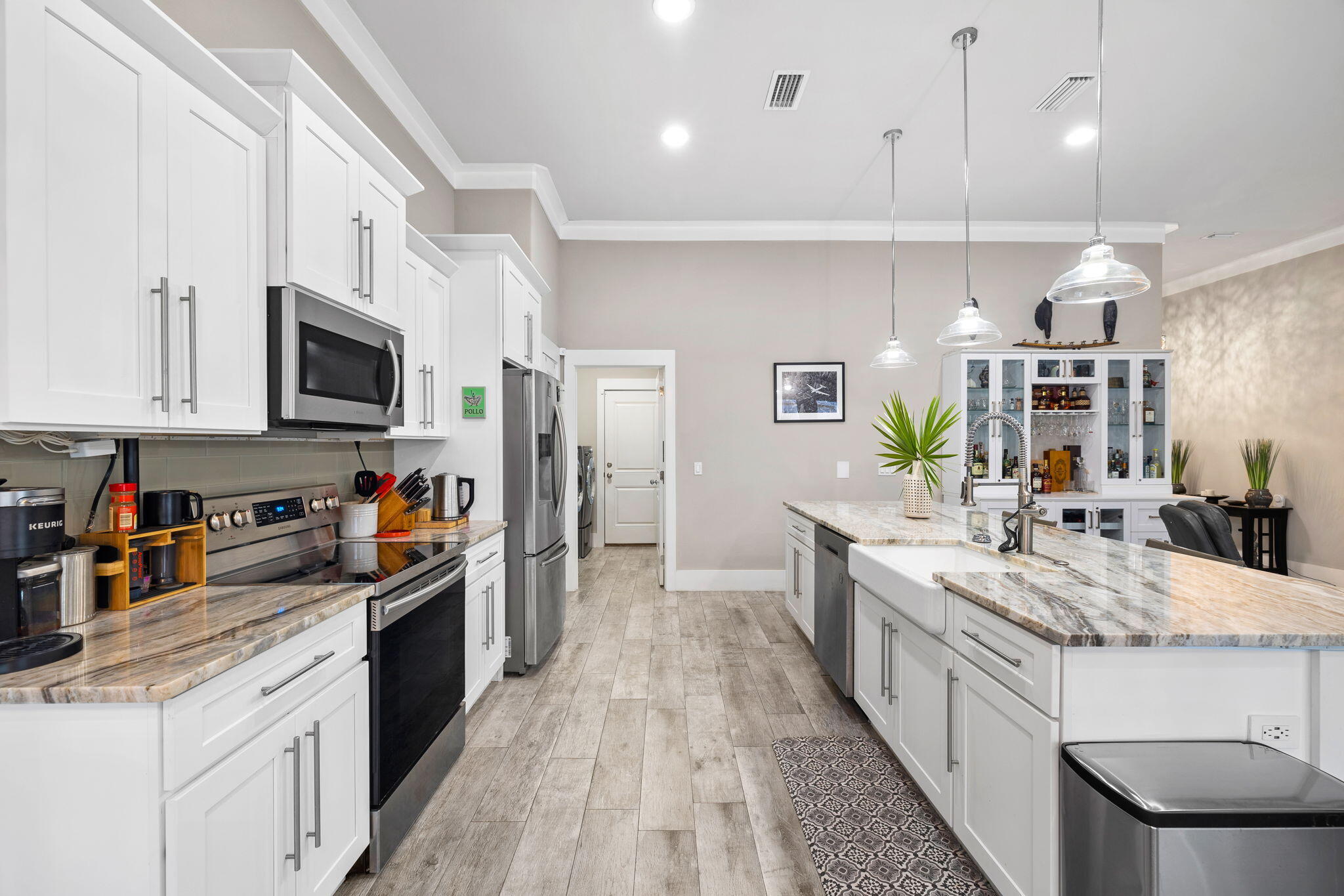 Kitchen with white cabinets, stainless appliances, and a large stone island with farmhouse sink.