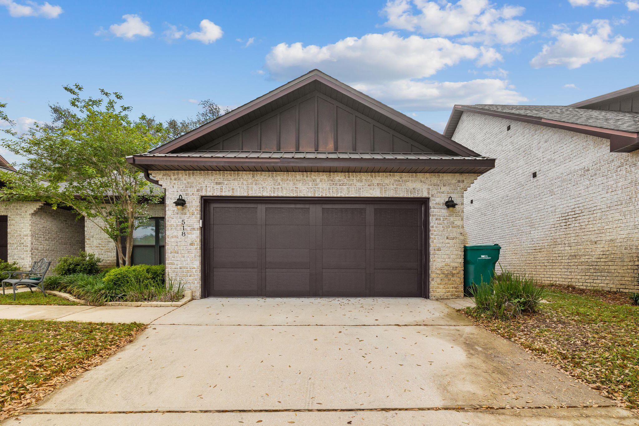 Brick home with a dark double garage door, wide driveway, and landscaped front yard.