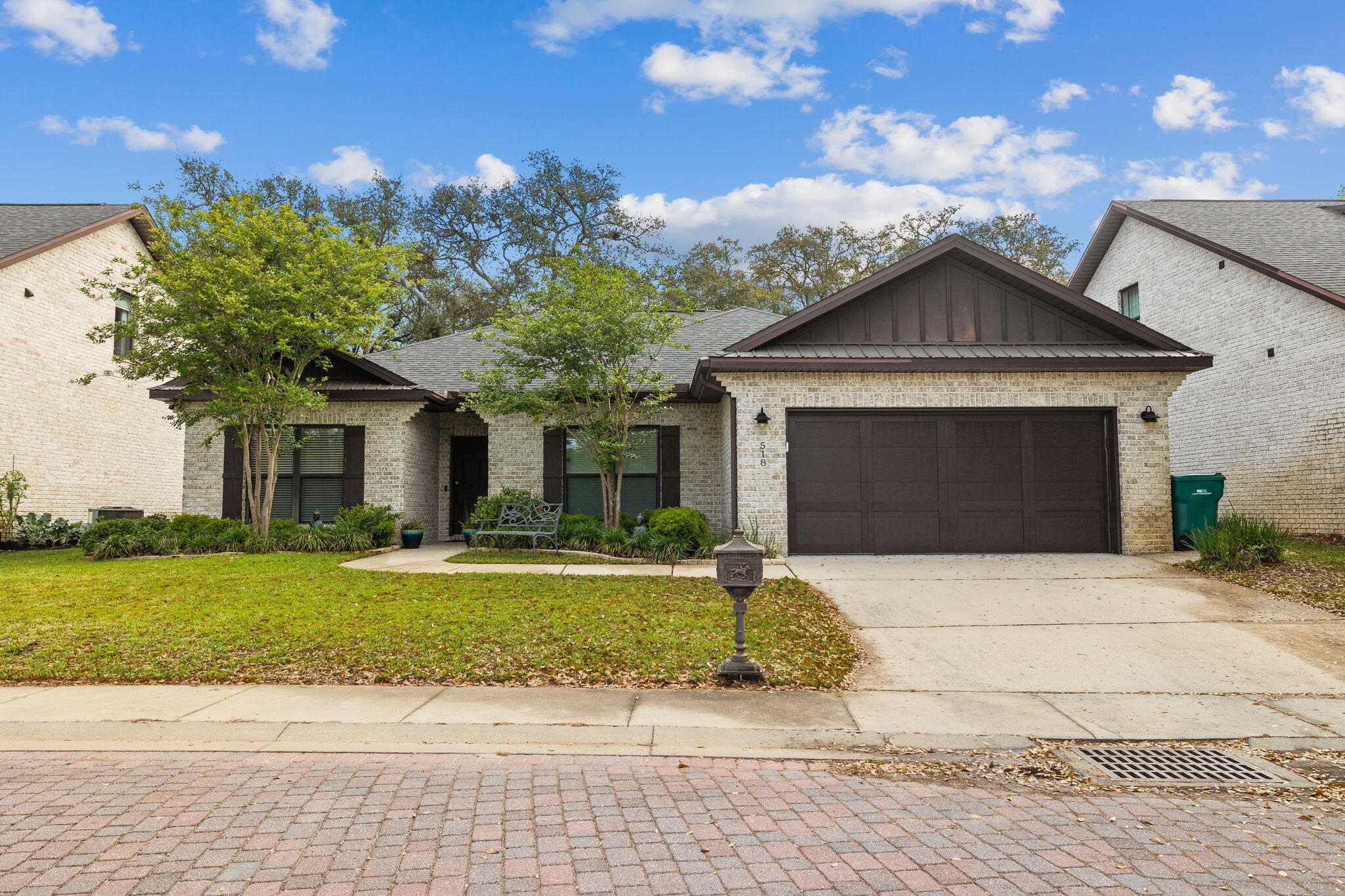 Single-story brick home with a dark double garage door, landscaped front lawn, and driveway.