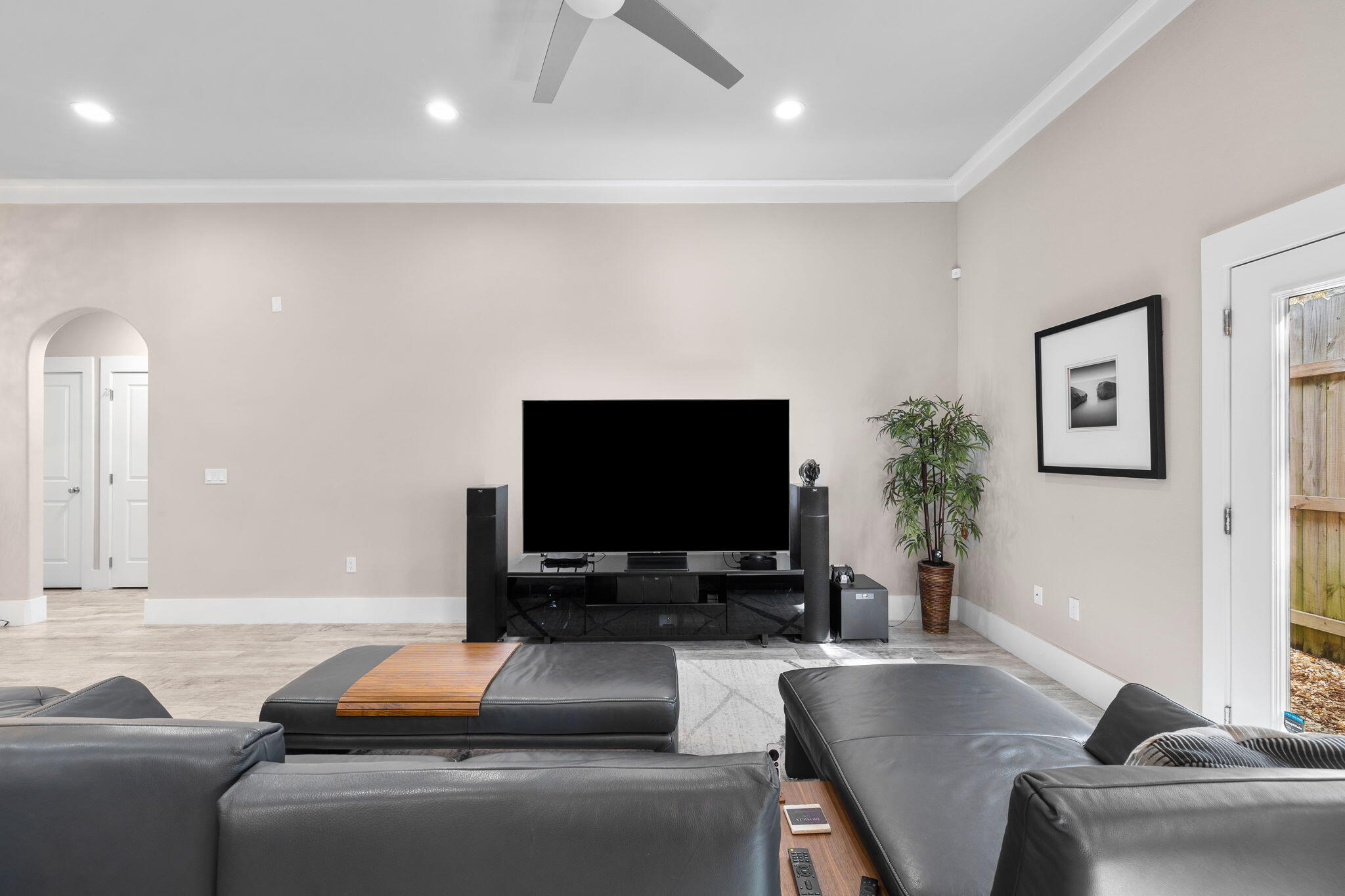 Living room with a large TV, black media console, and dark leather sectional seating.
