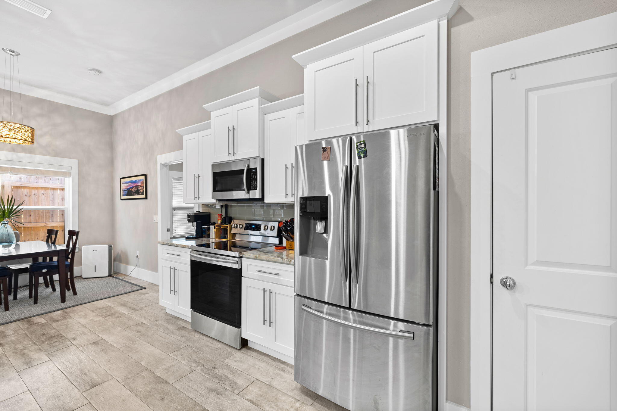 Kitchen with white cabinetry and stainless steel appliances beside an adjoining dining area.