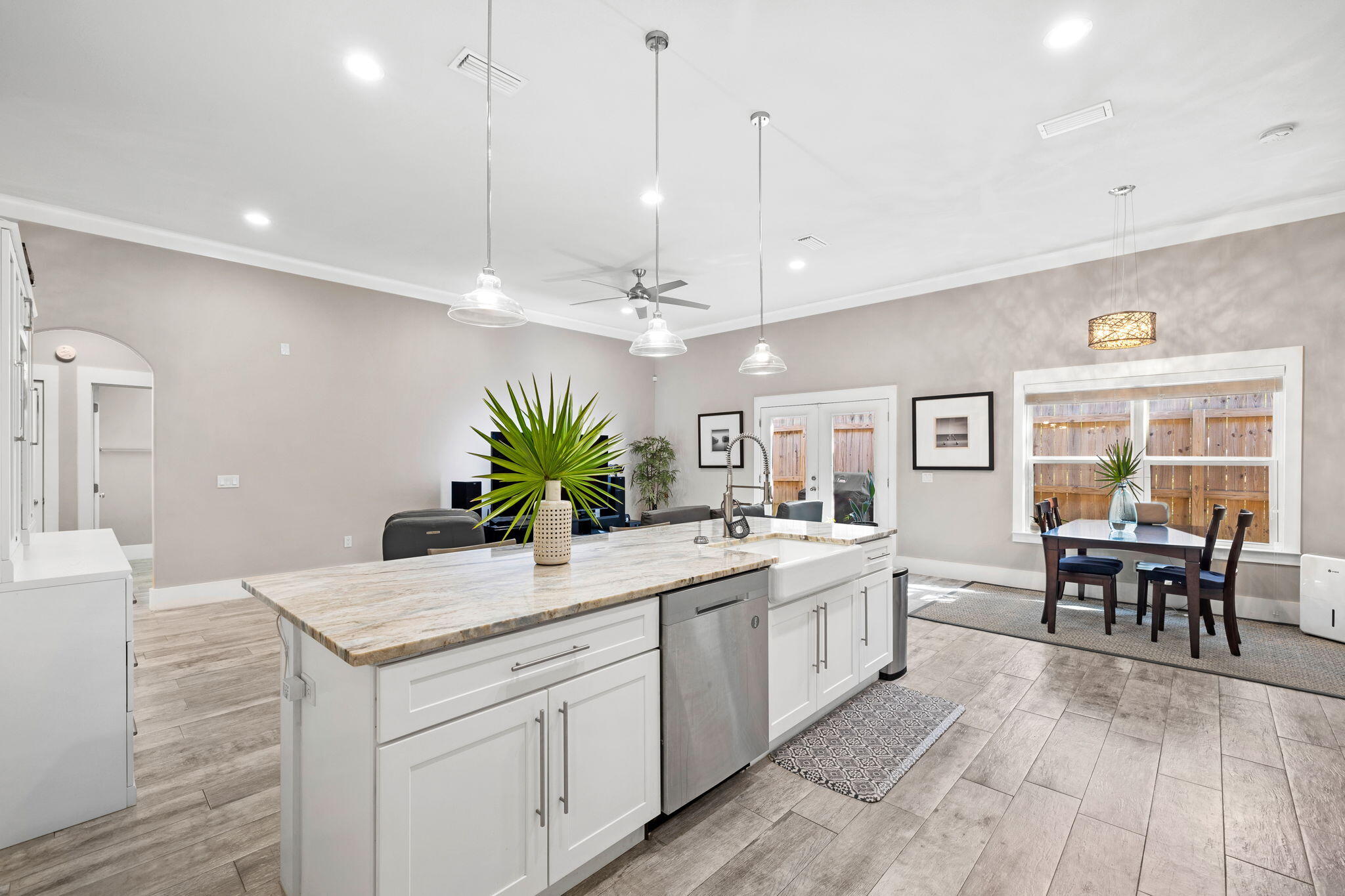 Open kitchen with a large stone island and farmhouse sink beside a dining area.