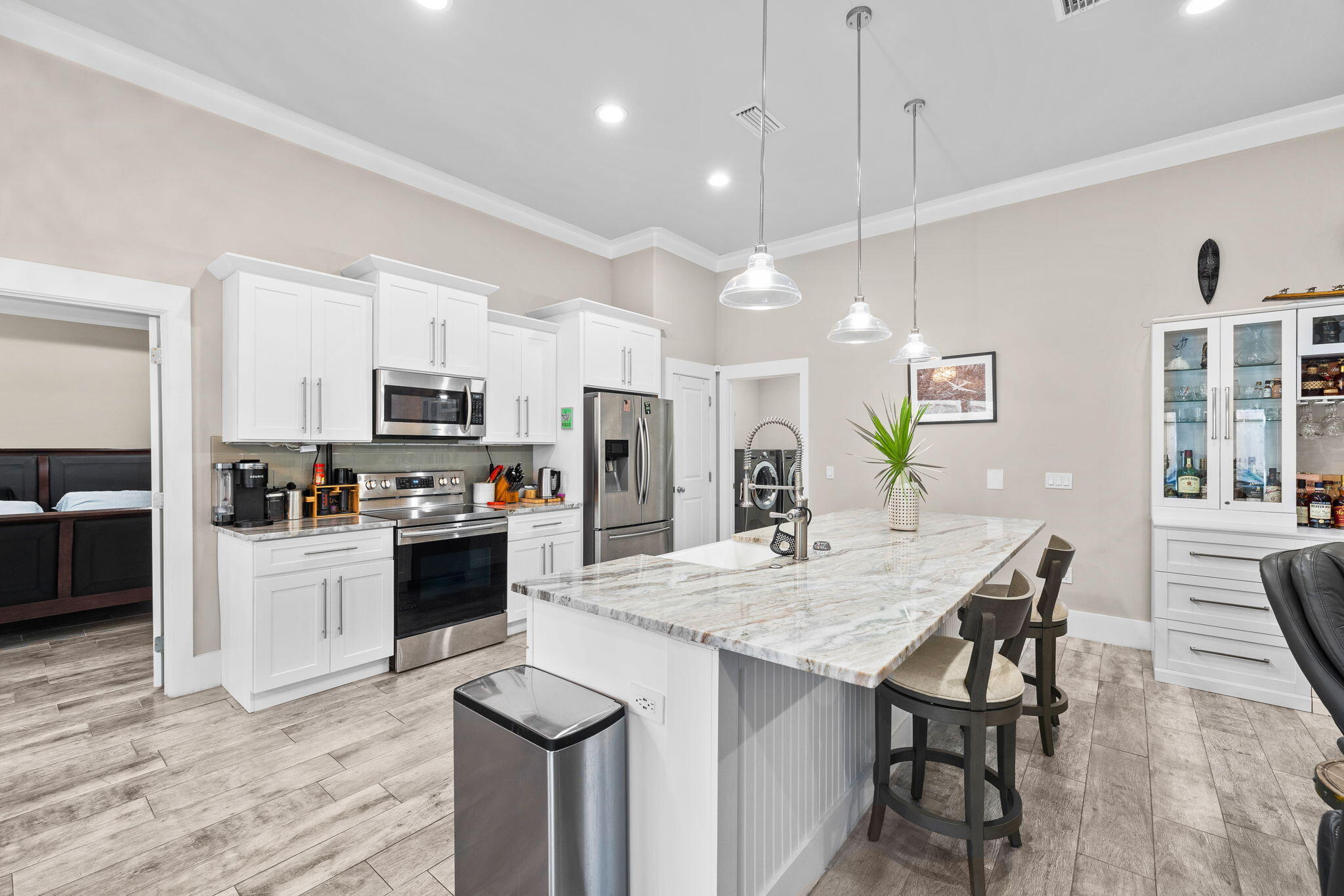 Kitchen with white cabinets, stainless steel appliances, and a large stone island with bar stools.