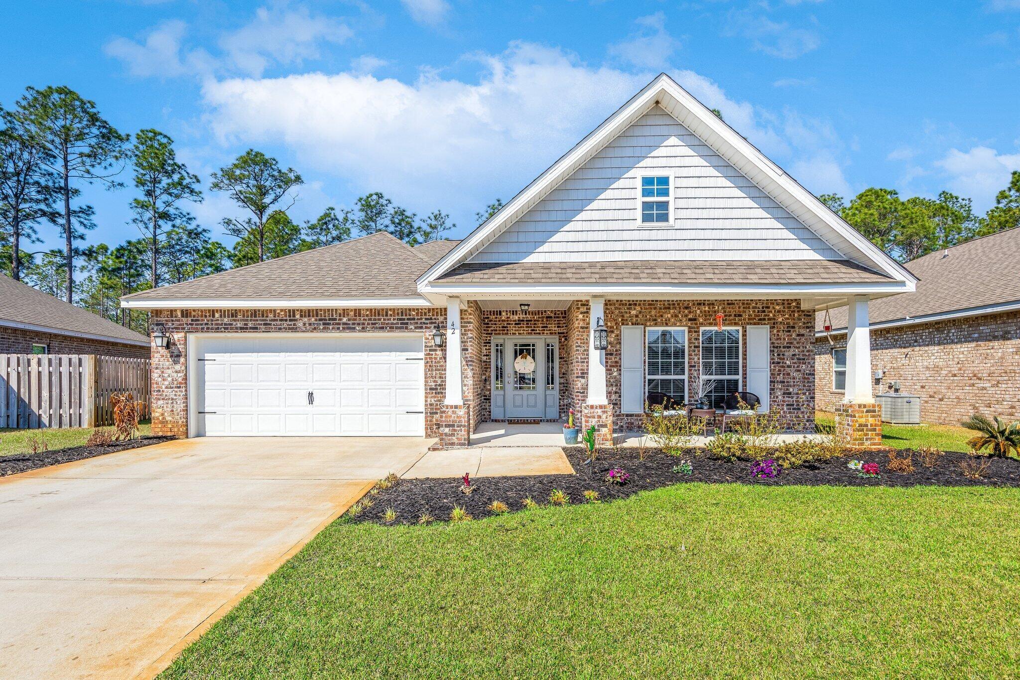 Brick house with a white gabled roof, two-car garage, and covered front porch.