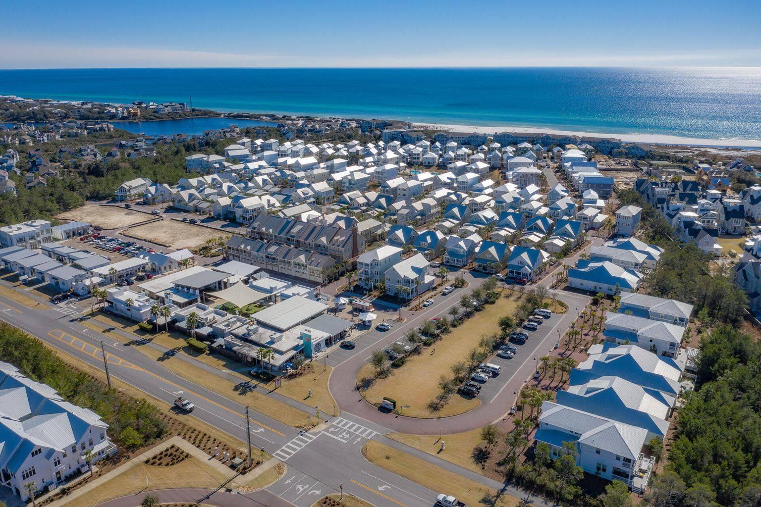 Aerial view of a coastal neighborhood with rows of homes beside blue ocean water.