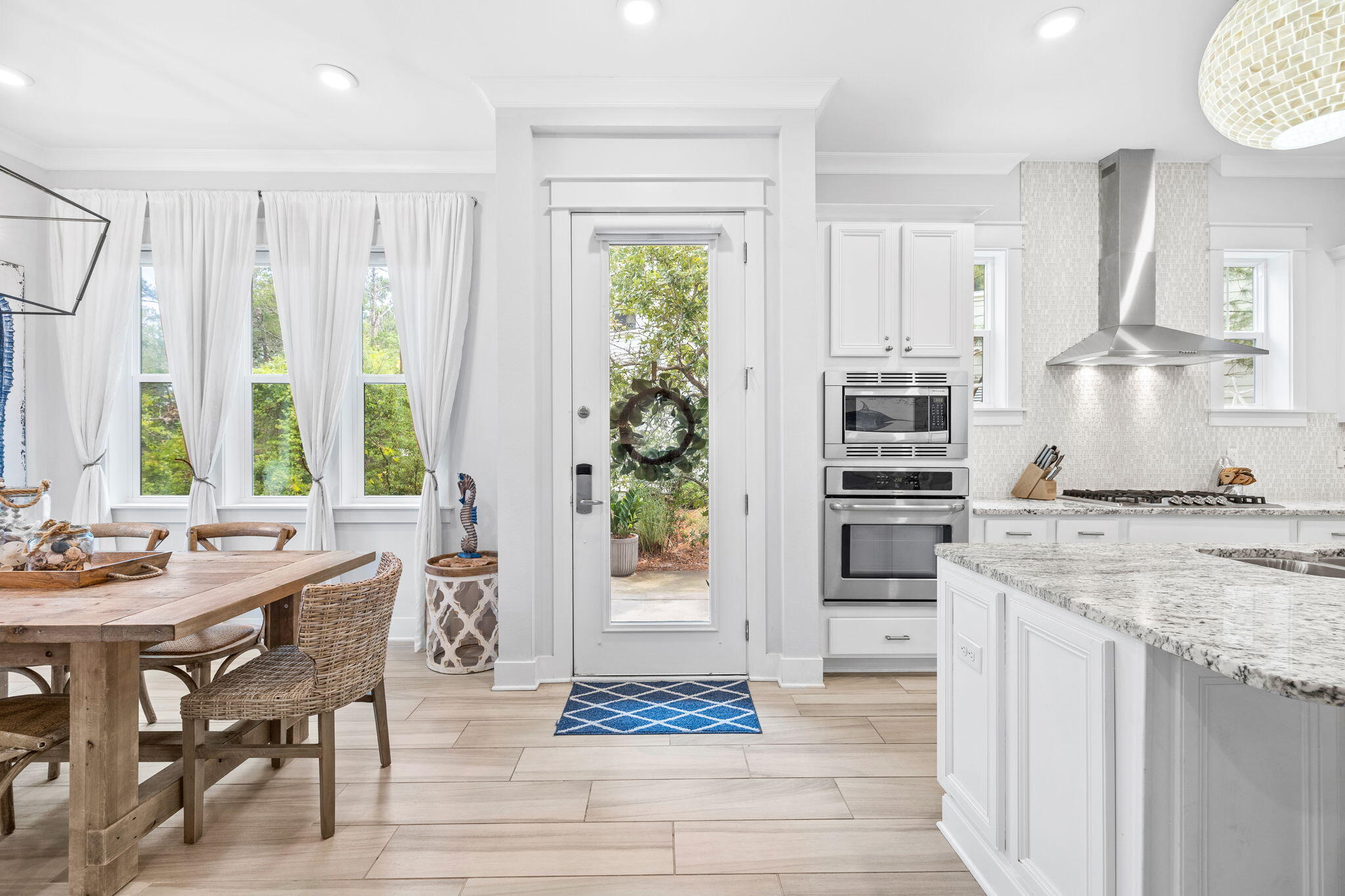 Open kitchen and dining area with a granite island, stainless appliances, and a glass-paneled door.