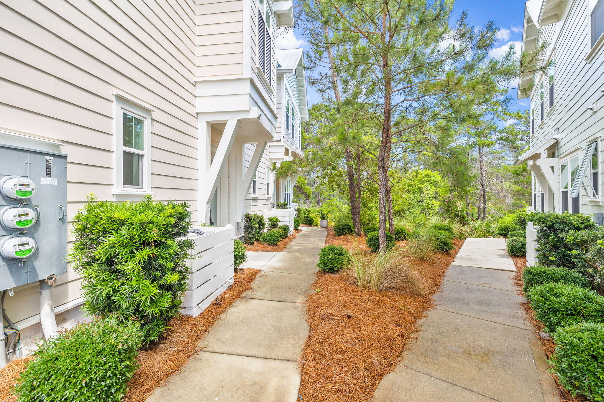 Concrete walkways run between light-colored residences and landscaped pine trees.