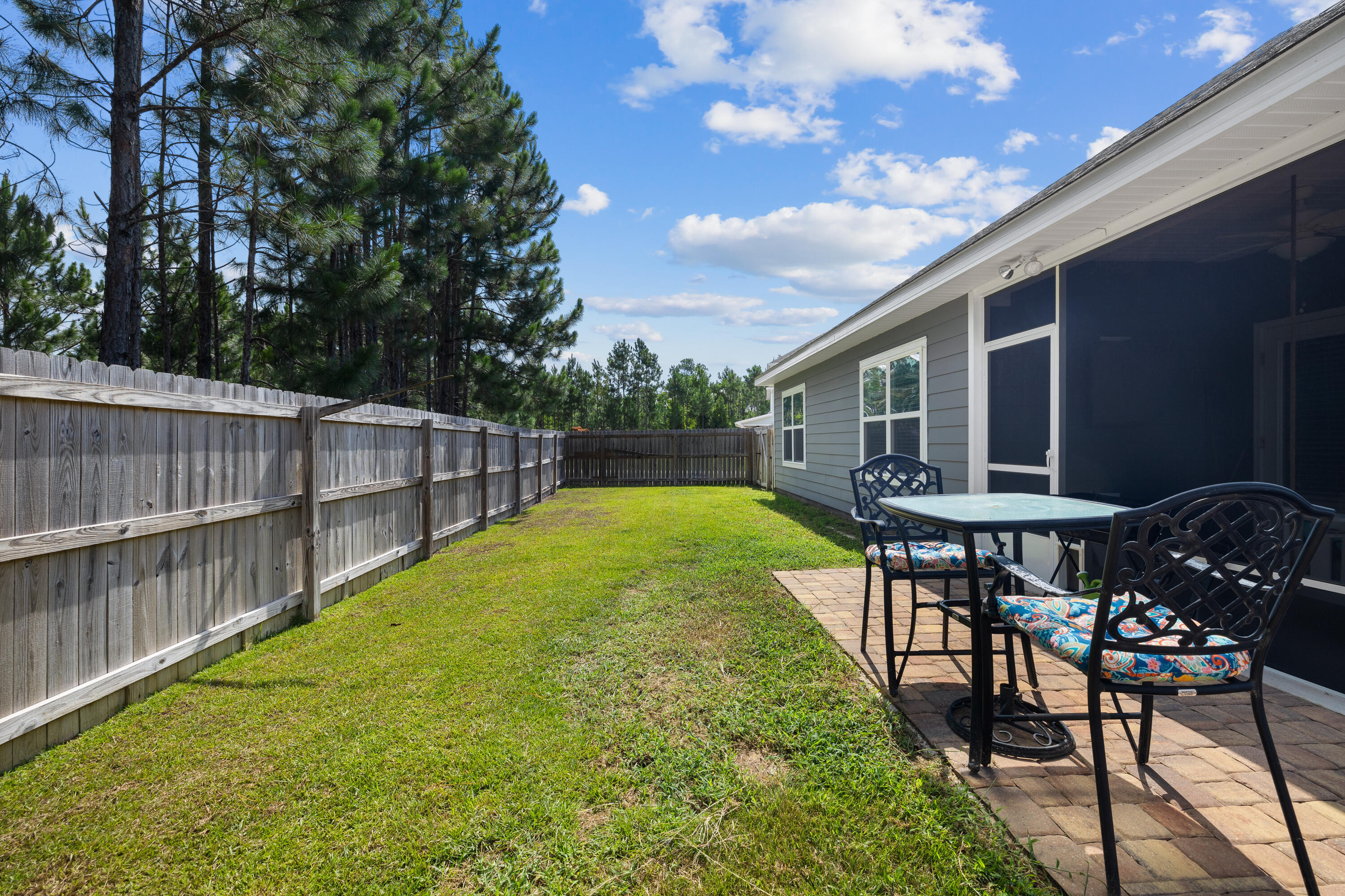 Fenced backyard with a brick patio, outdoor dining set, and screened porch.