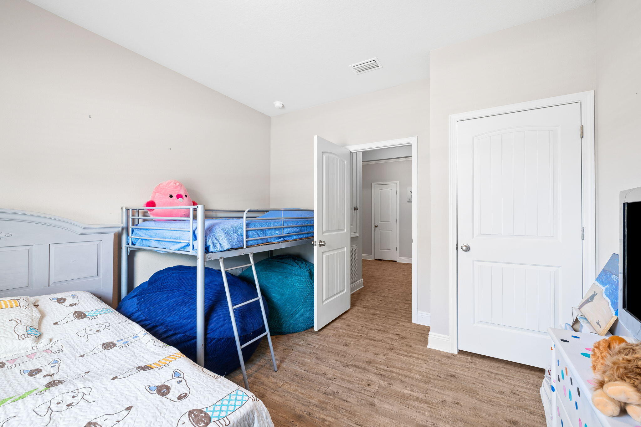 Children’s bedroom with a metal bunk bed, blue bedding, and beanbag chairs underneath.