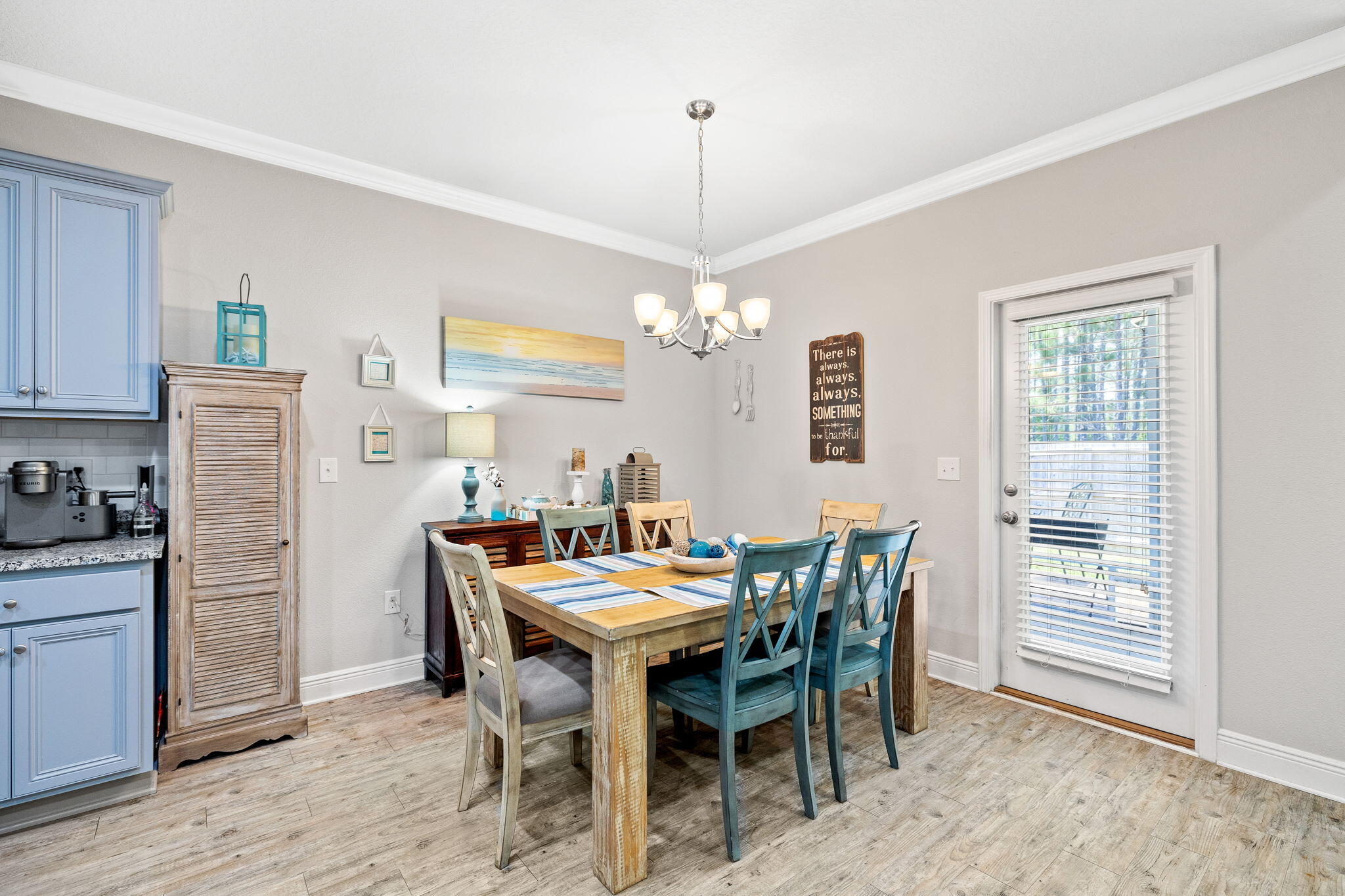 Dining area with a rustic wood table, blue cross-back chairs, and a glass door with blinds.
