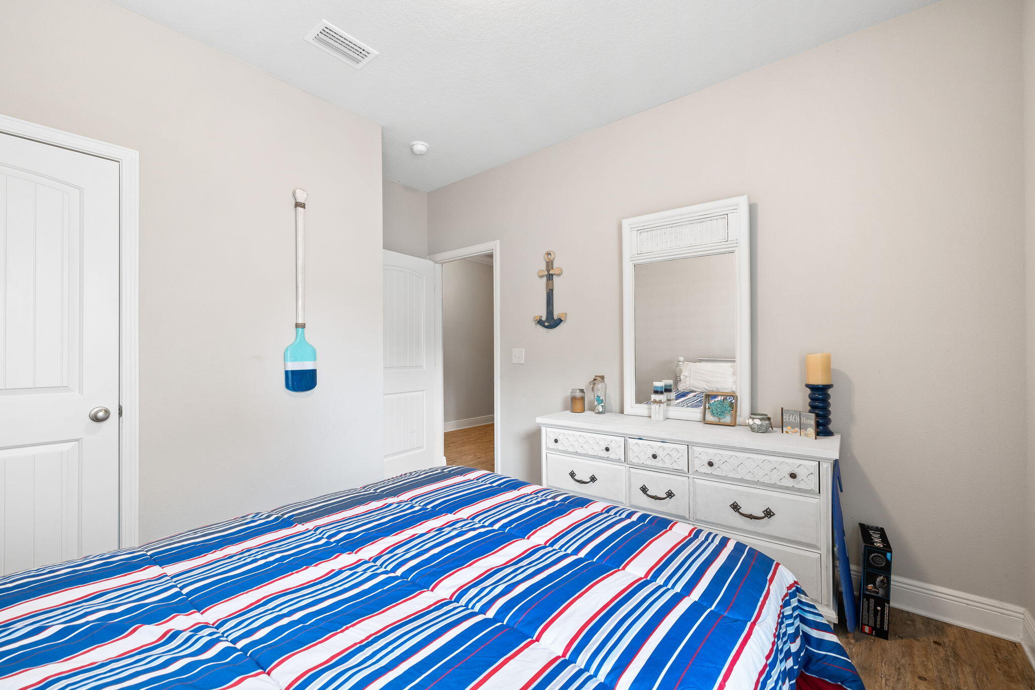 Bedroom with bold blue, white, and red striped bedding and nautical decor.