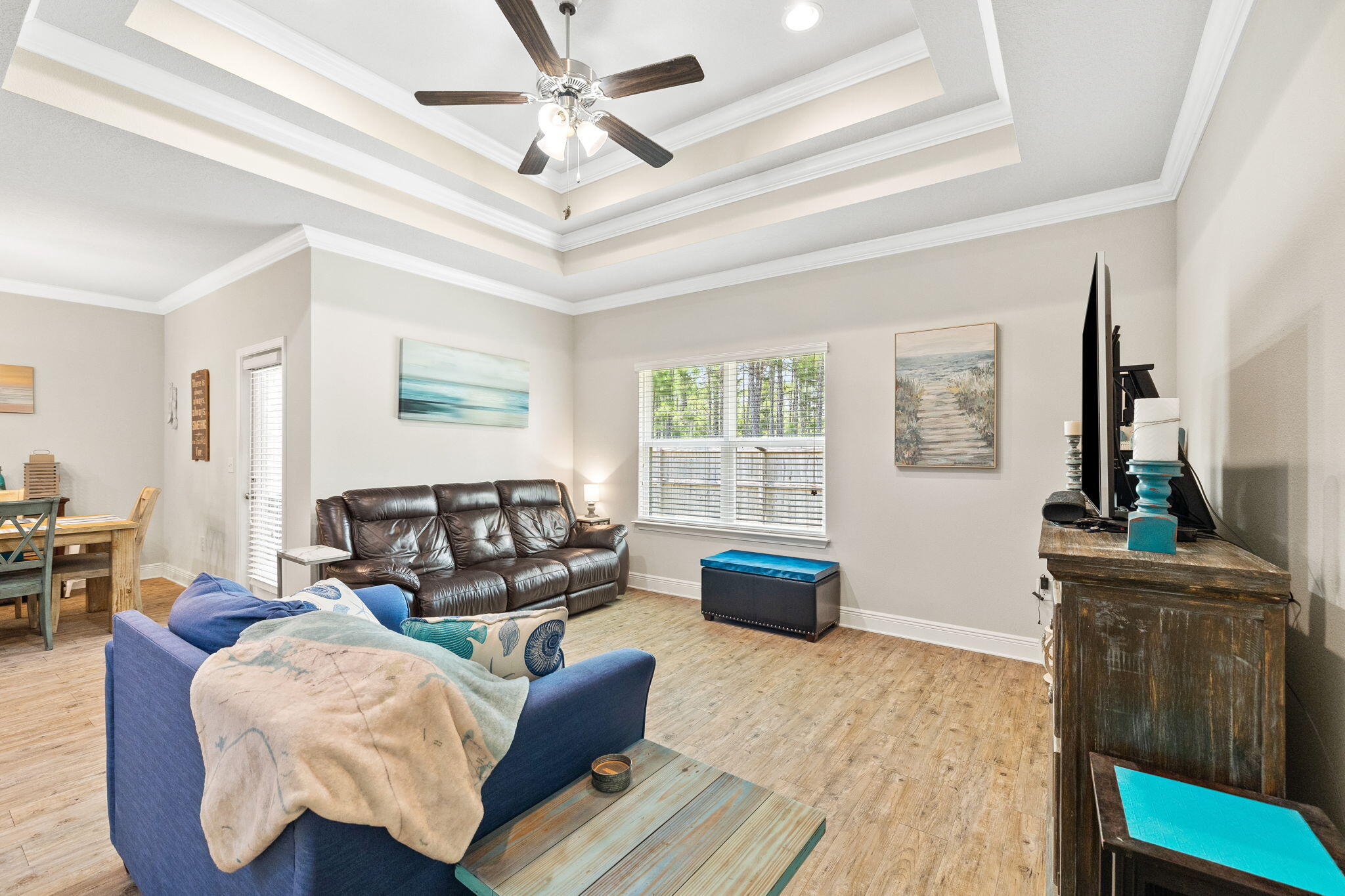 Living room with a tray ceiling, leather sofa, blue seating, and a window with blinds.