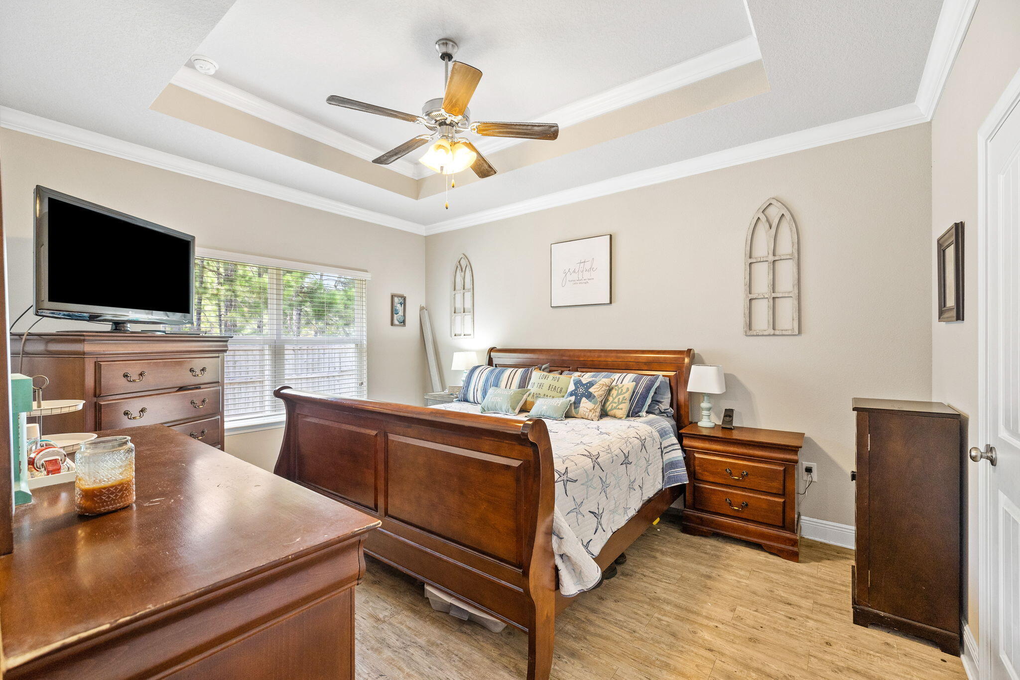 Bedroom with a dark wood sleigh bed, starfish bedding, matching dressers, and a tray ceiling.