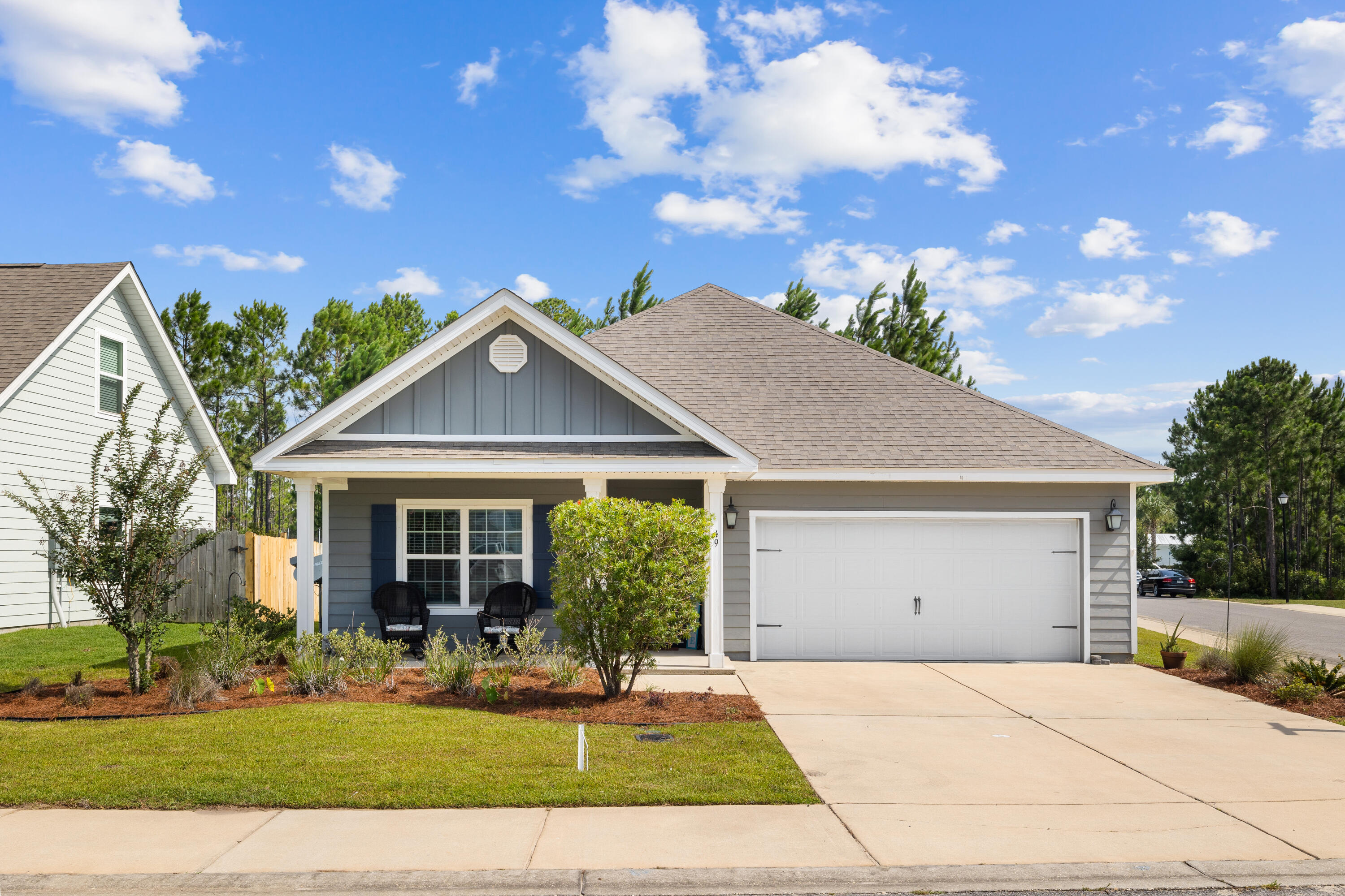 Gray single-story home with an attached two-car garage, covered porch, and landscaped front lawn.