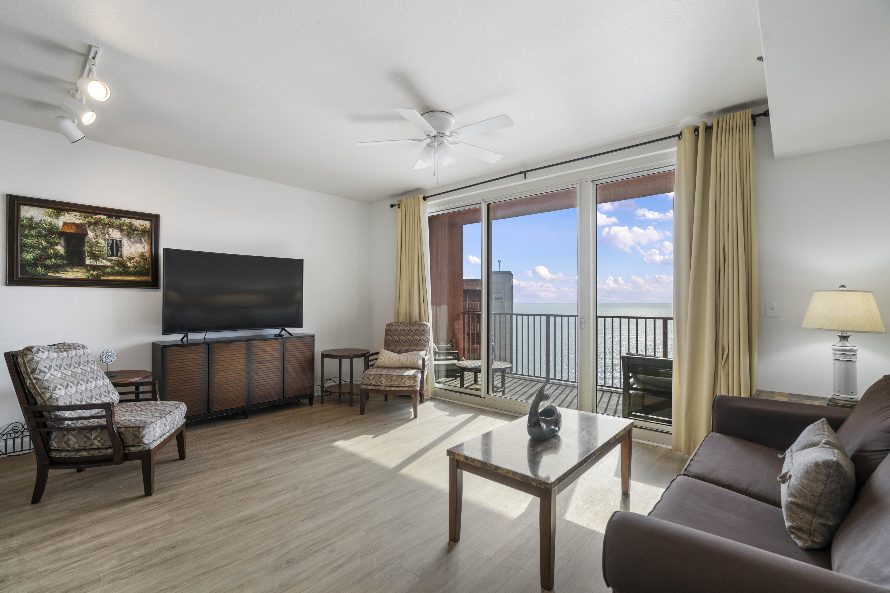 Furnished living room with sliding doors opening to a balcony overlooking the water.