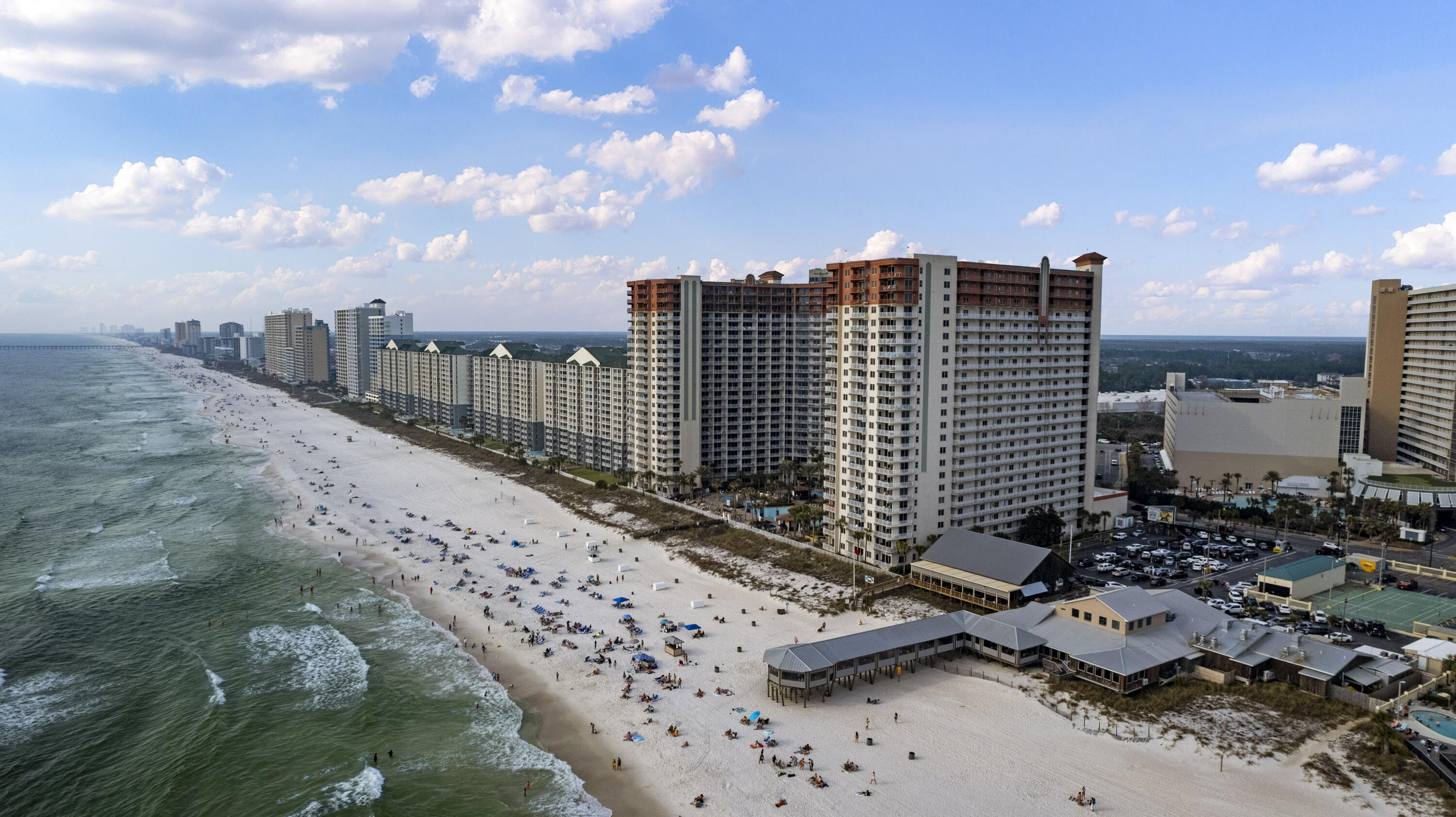Beachfront condominium towers beside a wide sandy beach and Gulf waters.